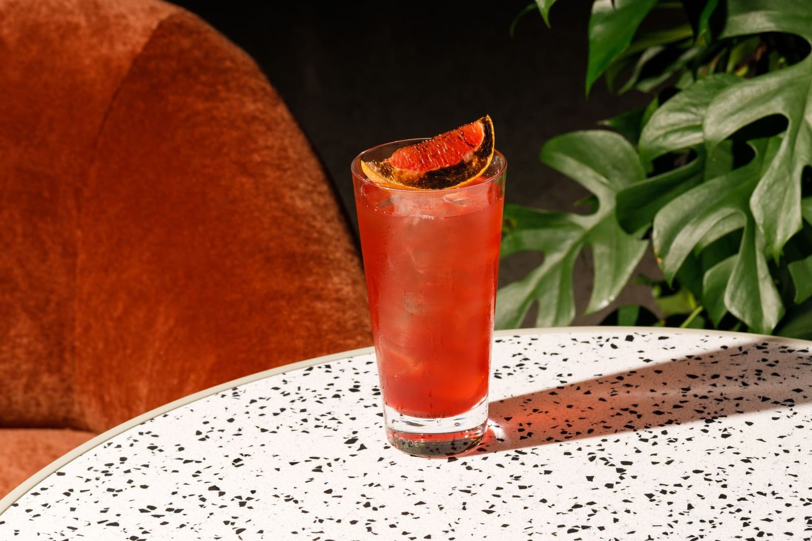 Donkerrode cocktail in een glas met een dramatische achtergrond van zwarte stof.