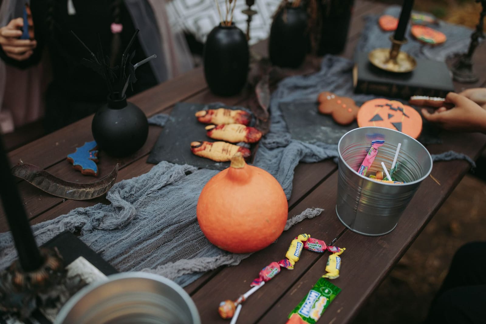 Versierde feesttafel met kaarsen, spinnenwebben en glazen gevuld met gekleurde drankjes.