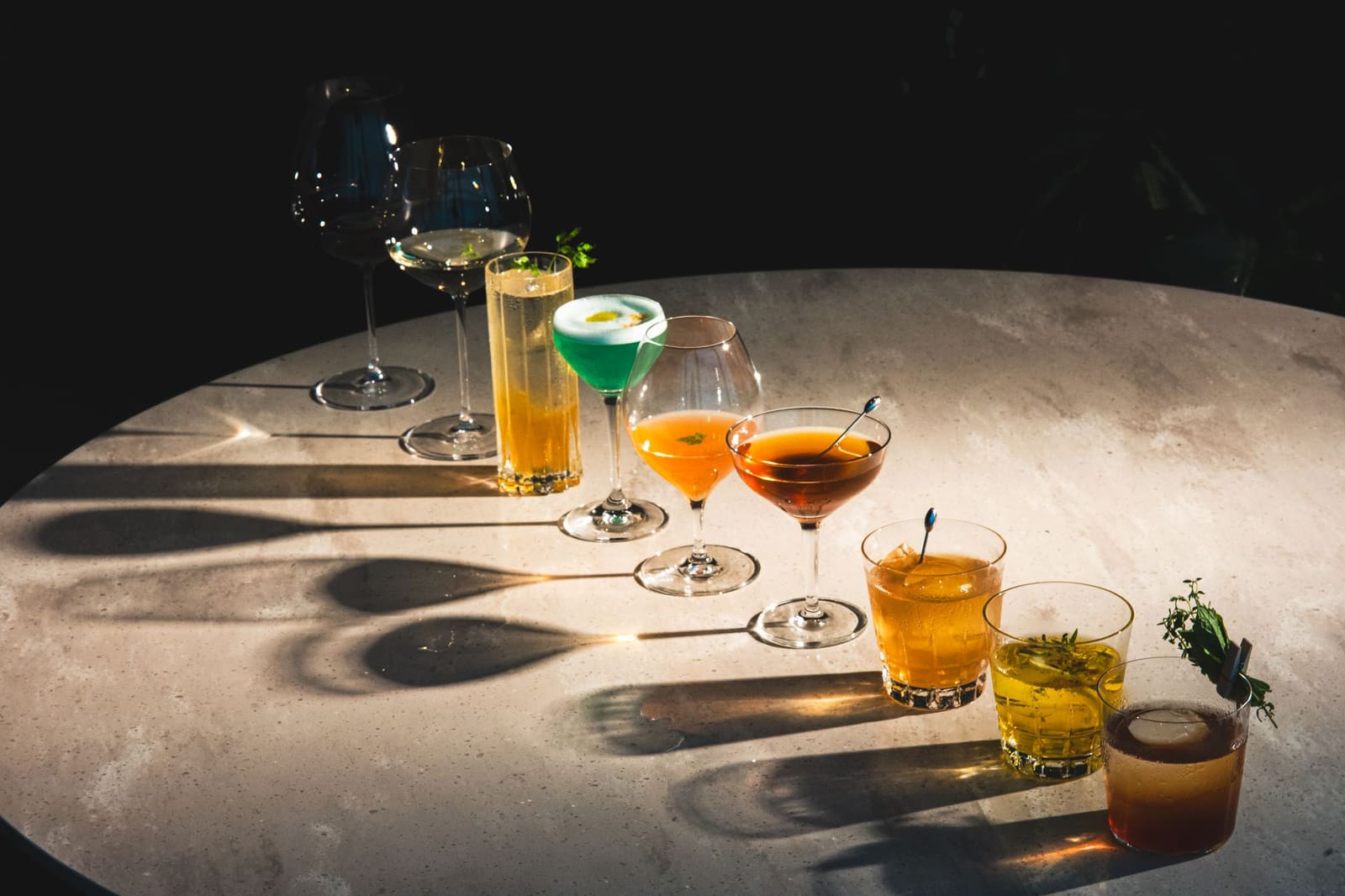 Rij gekleurde cocktails met garnering op een bar