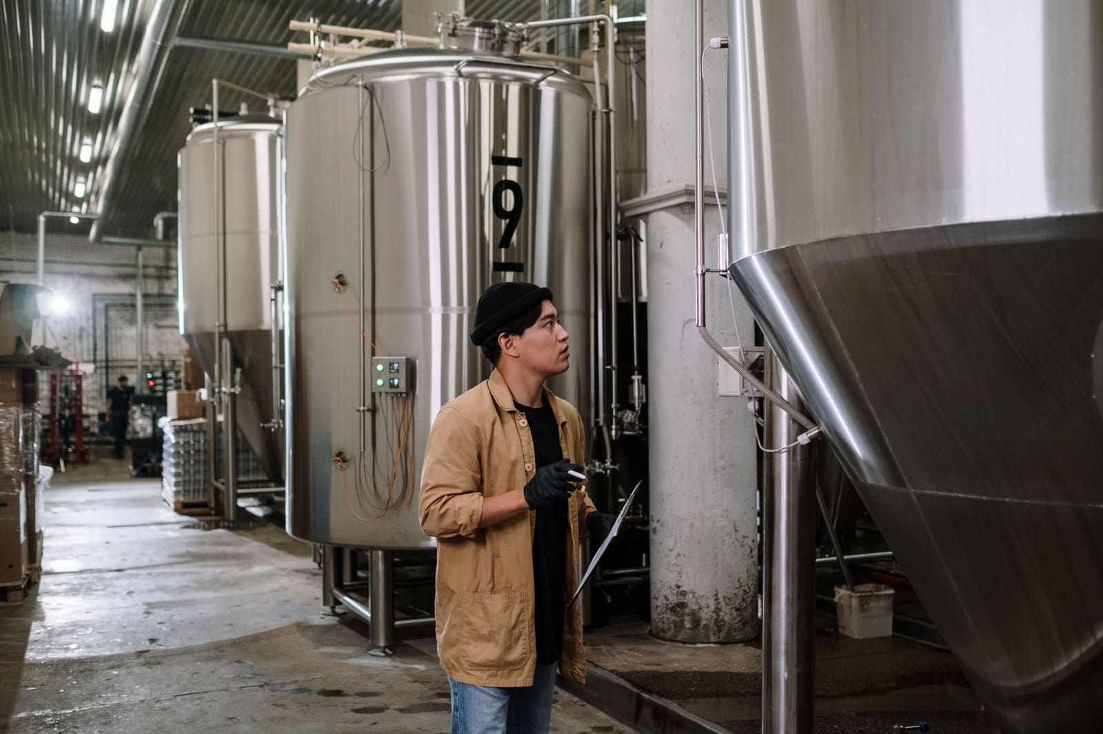 Grote roestvrijstalen bierketels in een brouwerij met warm licht op de tanks