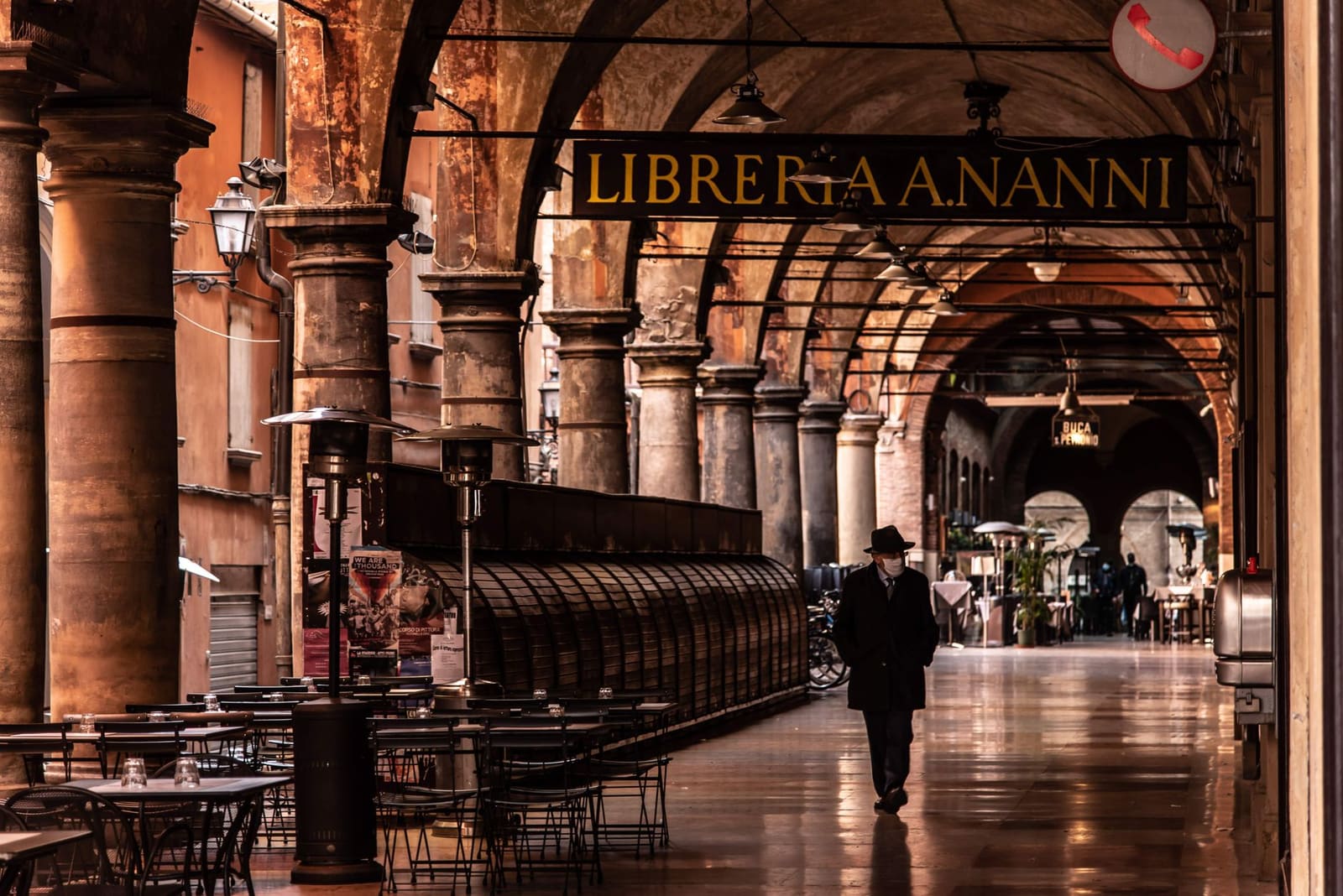 Oude zuilengangen met bogen en stenen vloeren in een Italiaanse stad.
