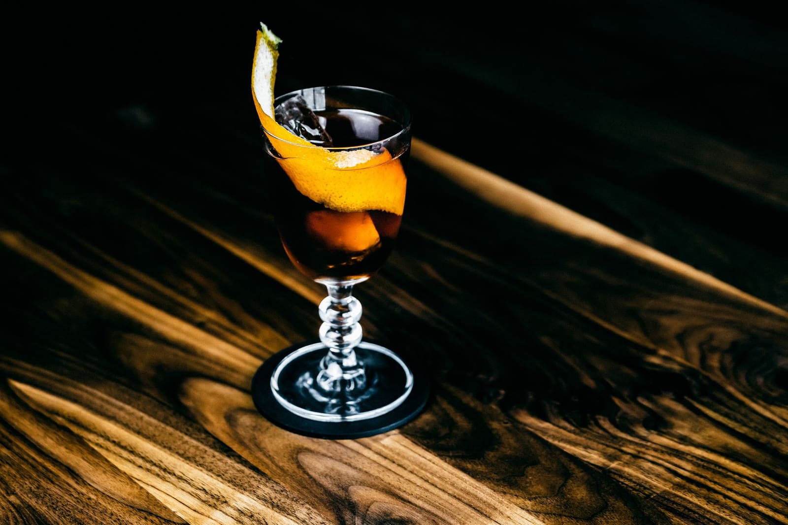 Detailfoto van een cocktail met ijs en citrusgarnering op tafel