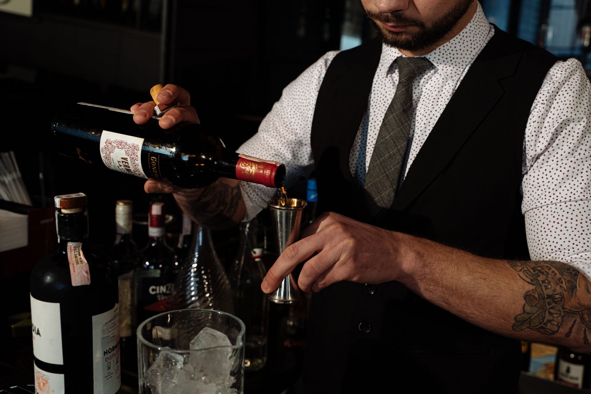 bartender proeft met een lepel de balans van een cocktail achter de bar