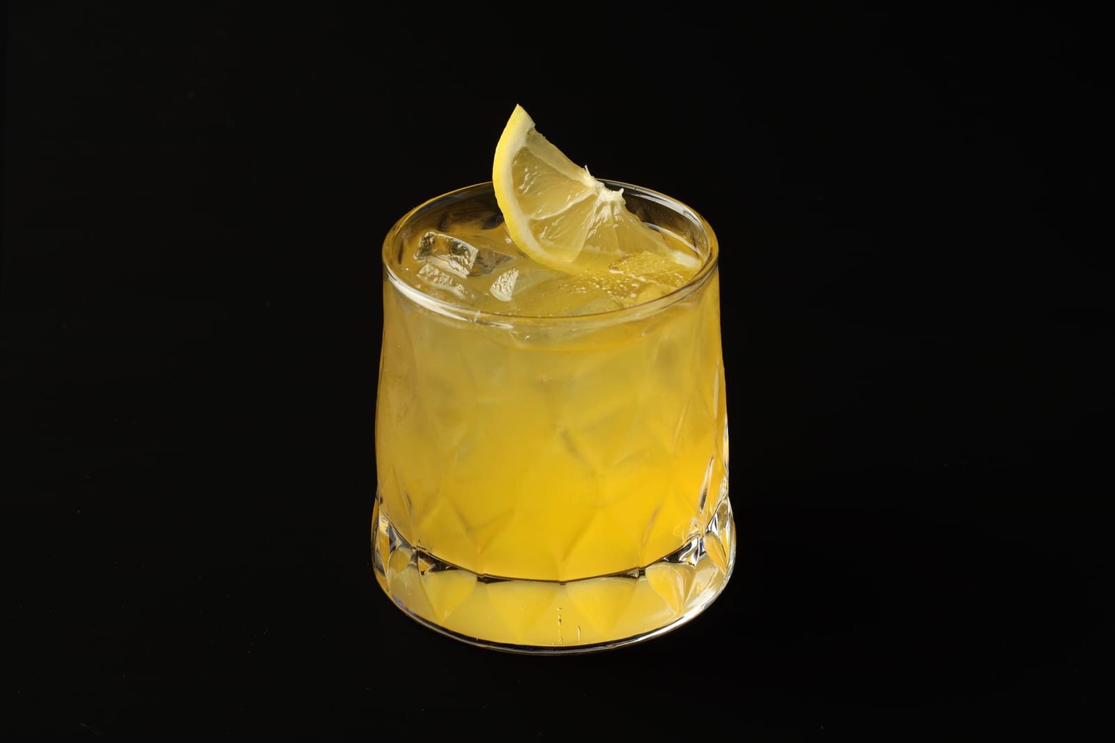 Een goudbruine cognac-cocktail met citroenschil in een cocktailglas op een bar