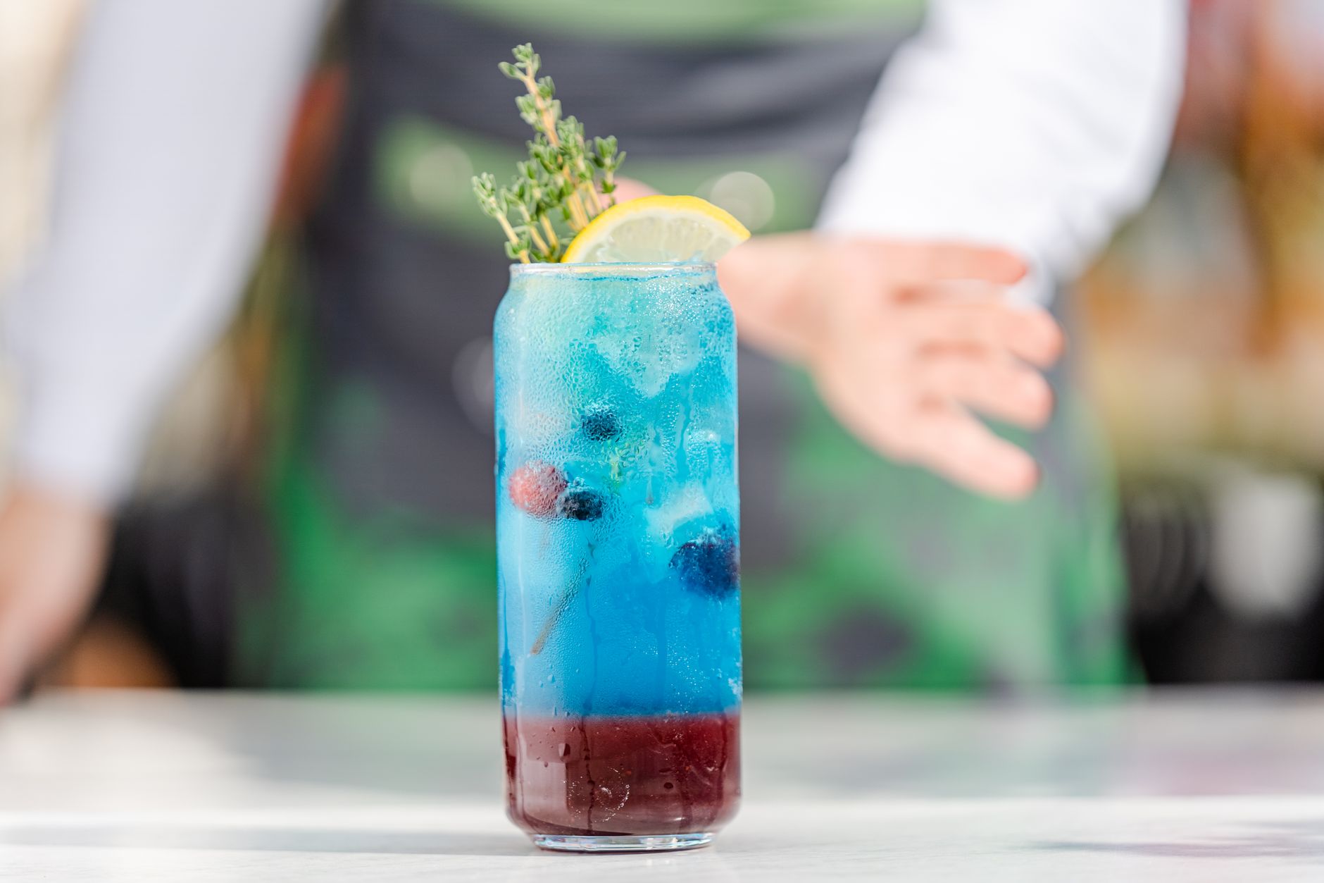 Bartender schenkt een verfijnde alcoholvrije cocktail met kruiden en garnish achter de bar