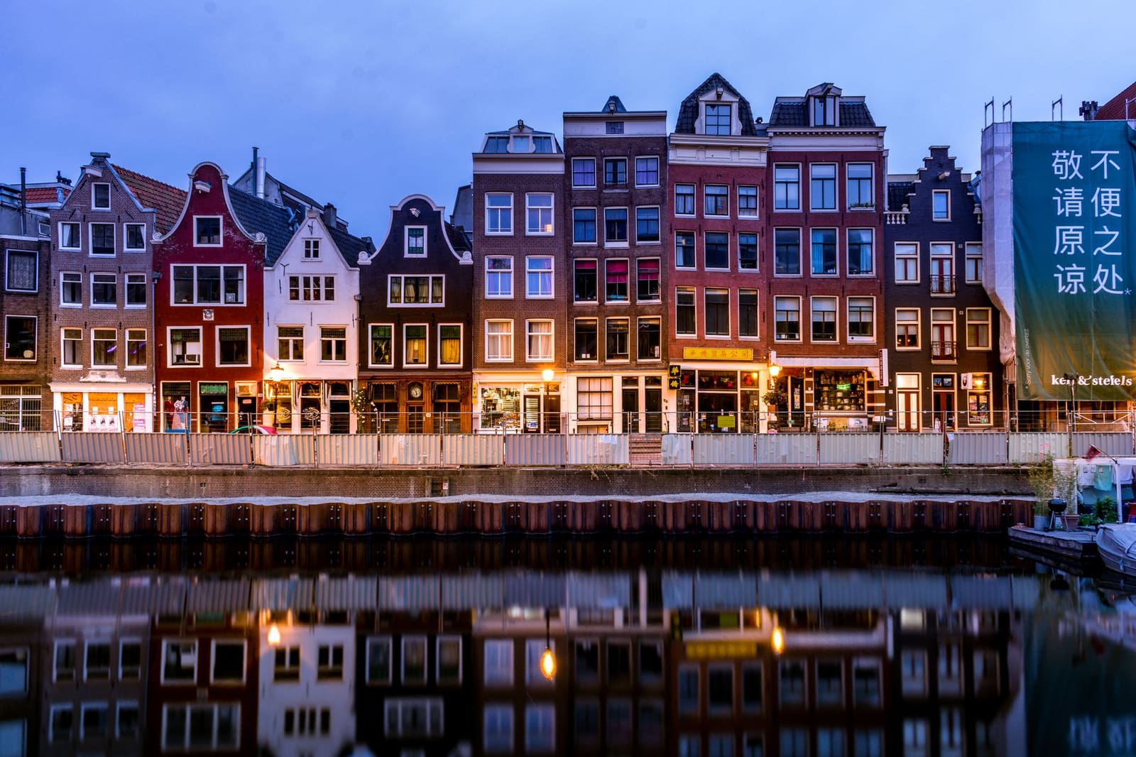 Amsterdamse grachtenpanden weerspiegeld in het water tijdens de gouden uurtjes
