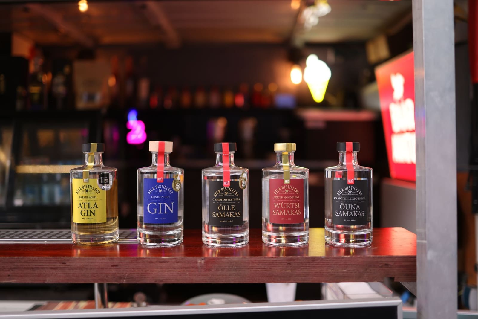 Rij gin en jeneverflessen uitgestald op een plank in een distilleerderij