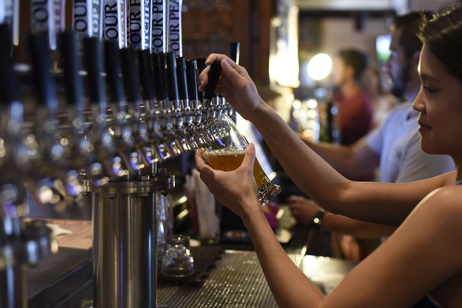 Twee glazen ambachtelijk bier naast elkaar op een houten bar