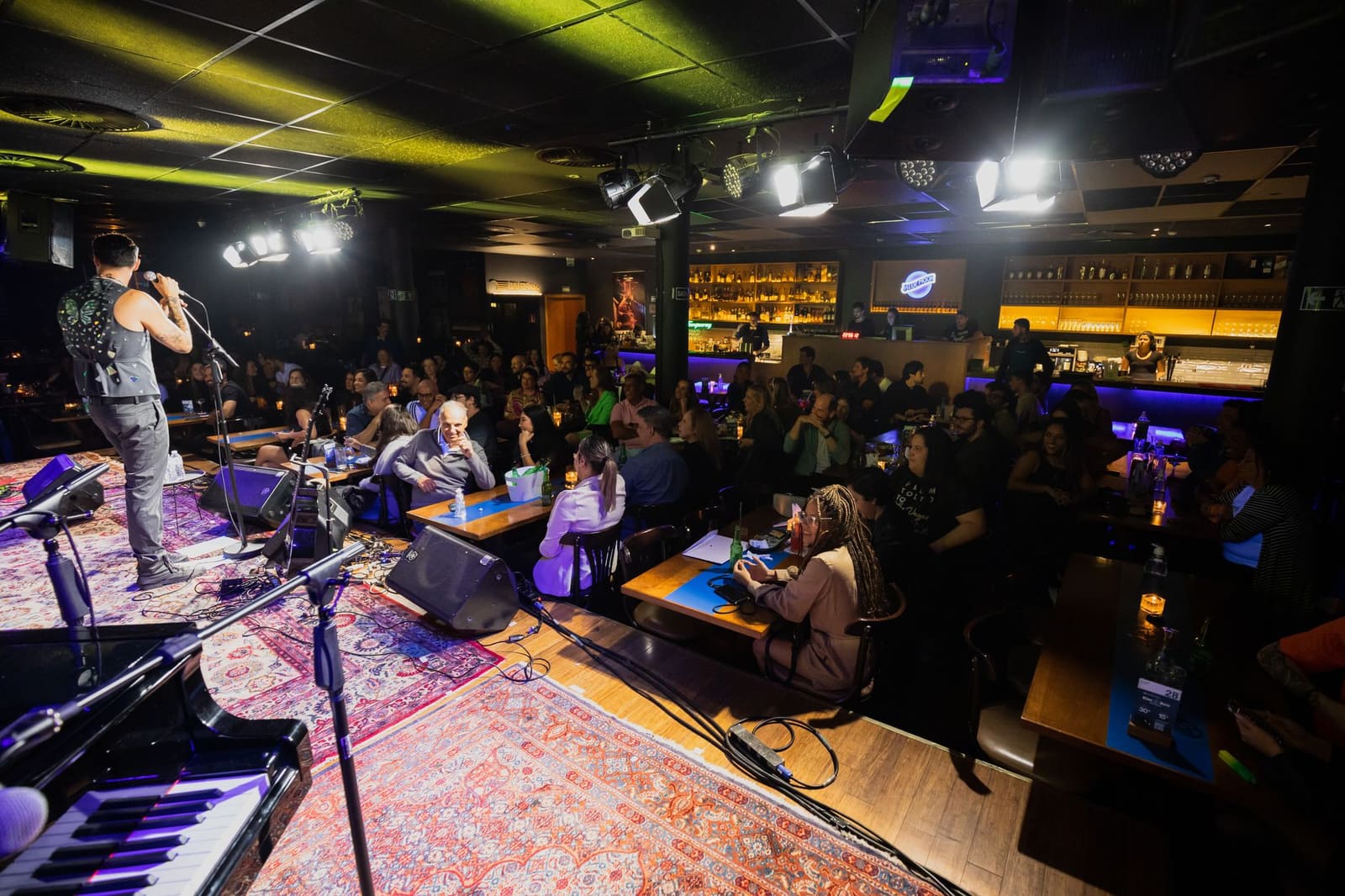 Publiek zit in een zaal met een verlicht podium tijdens een prijsuitreiking.