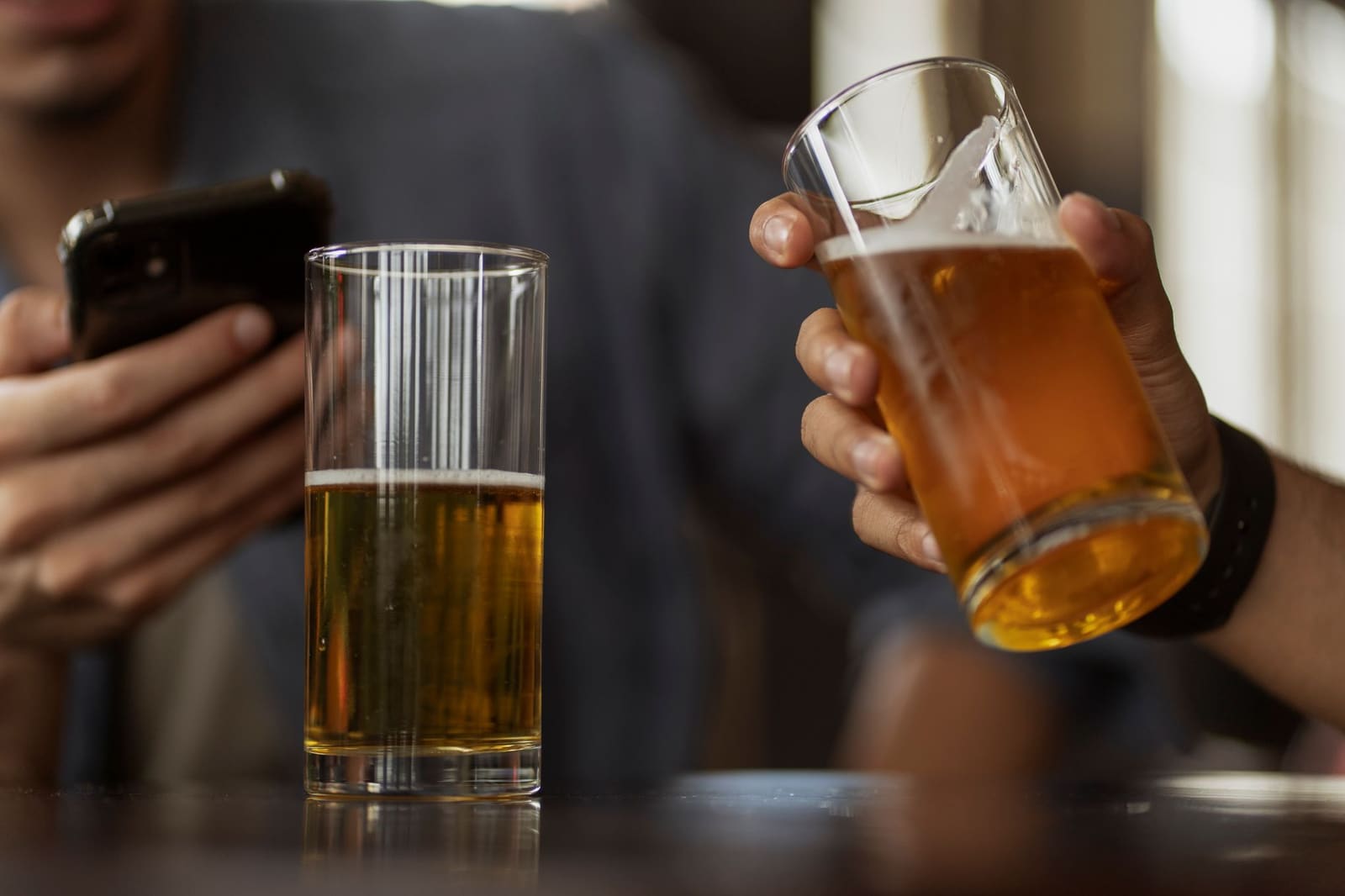 Close-up van een vol glas bier met schuimkraag op de bar