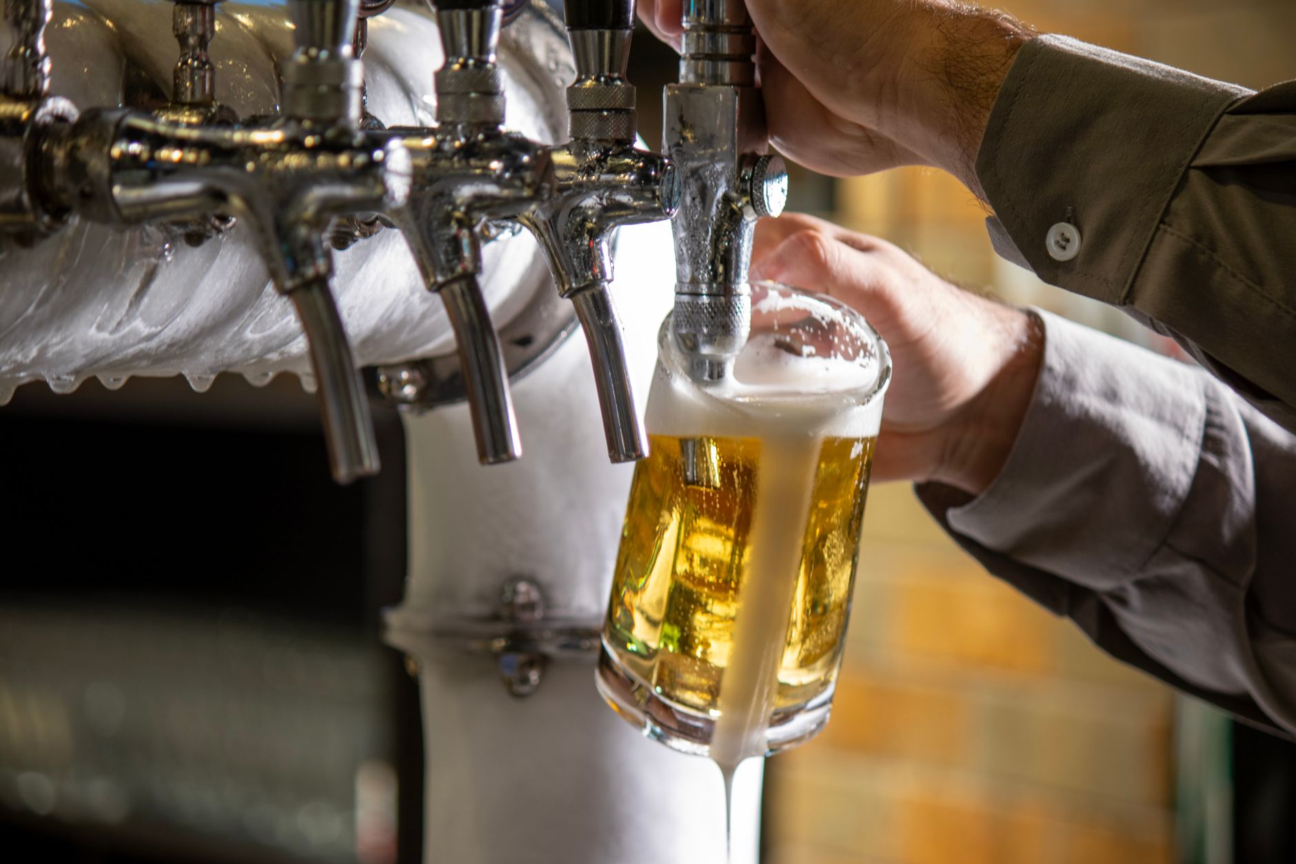 Bartender tapt een pilsje uit een biertap in een Britse pub