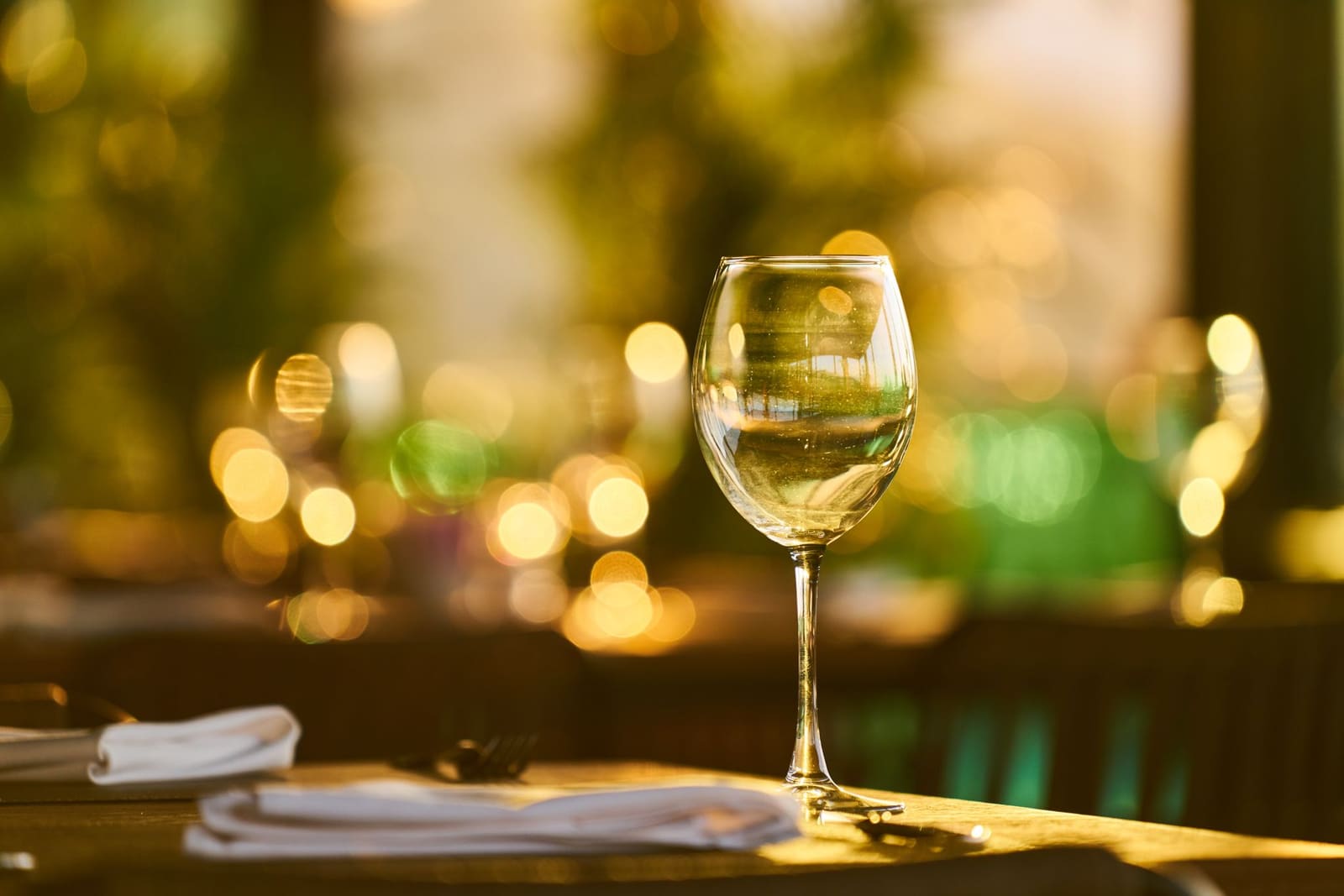 Een wijnglas op een restauranttafel met wazige lichtjes op de achtergrond.