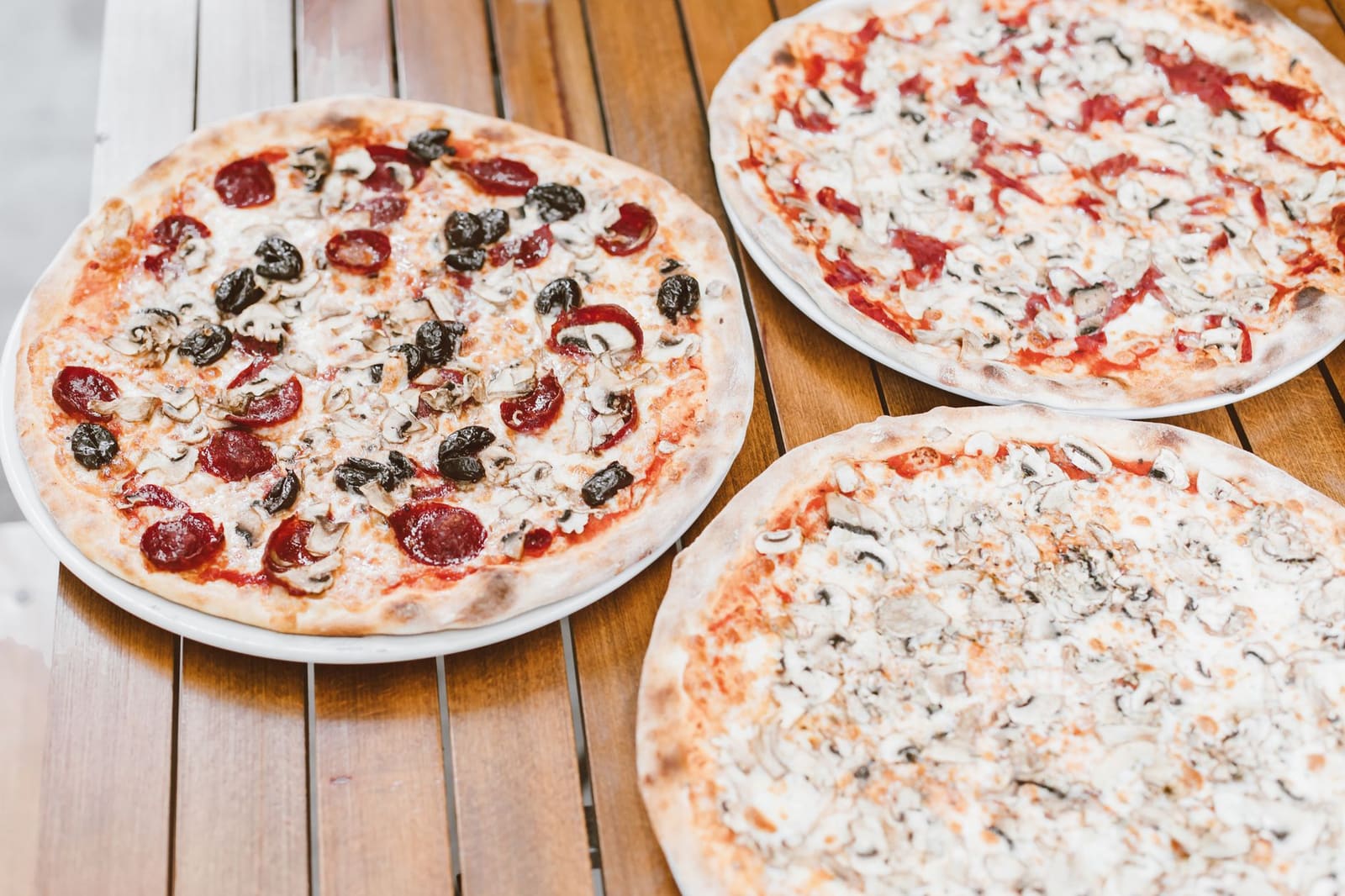 Een pizza met tomaat en mozzarella op een terrastafel, met een glas spritz ernaast.