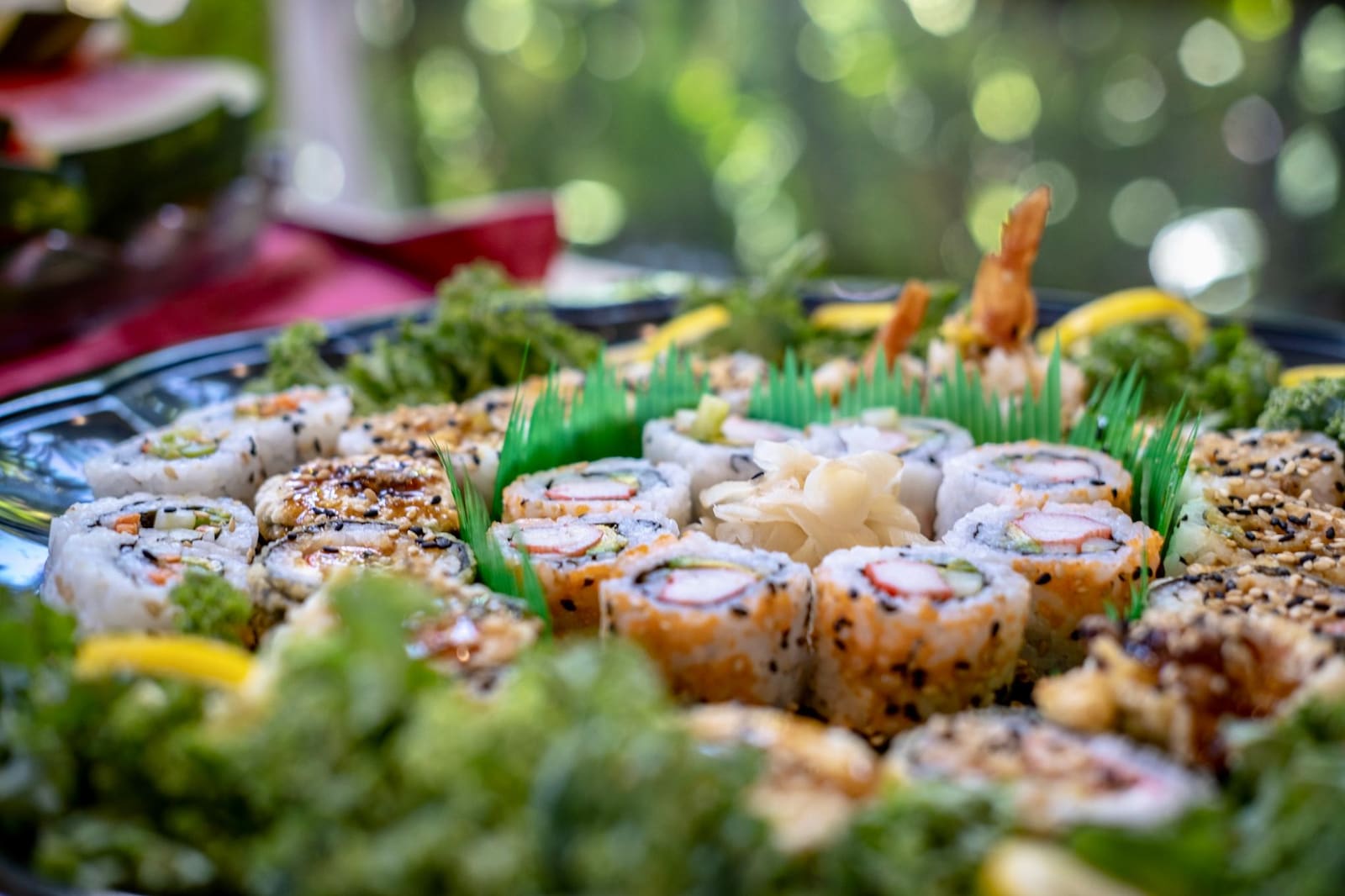 Een schaal met nigiri en maki, met roze gember en een klodder groene wasabi.