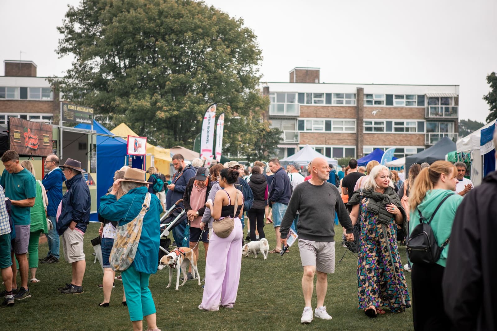 Bezoekers lopen tussen kraampjes van drankenmerken op een druk festival