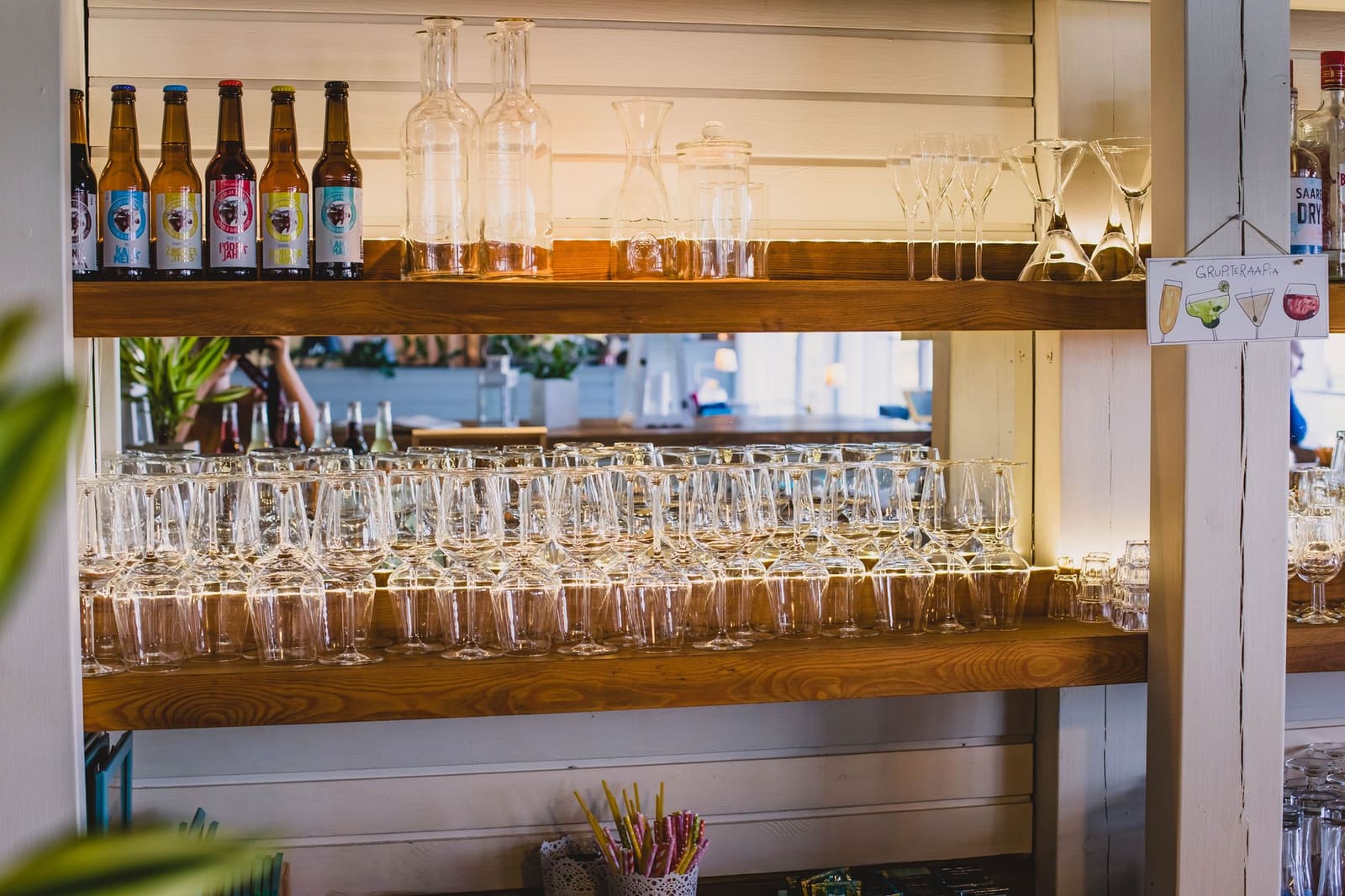 Planken met glazen en flessen in een bar, waaronder diverse cocktailglazen.