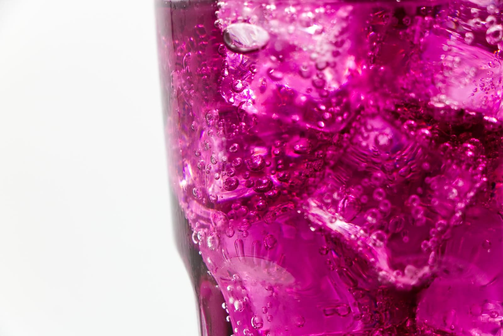 Een hoog highball glas gevuld met ijsblokjes en bruisende drank, met een limoenpartje aan de rand.