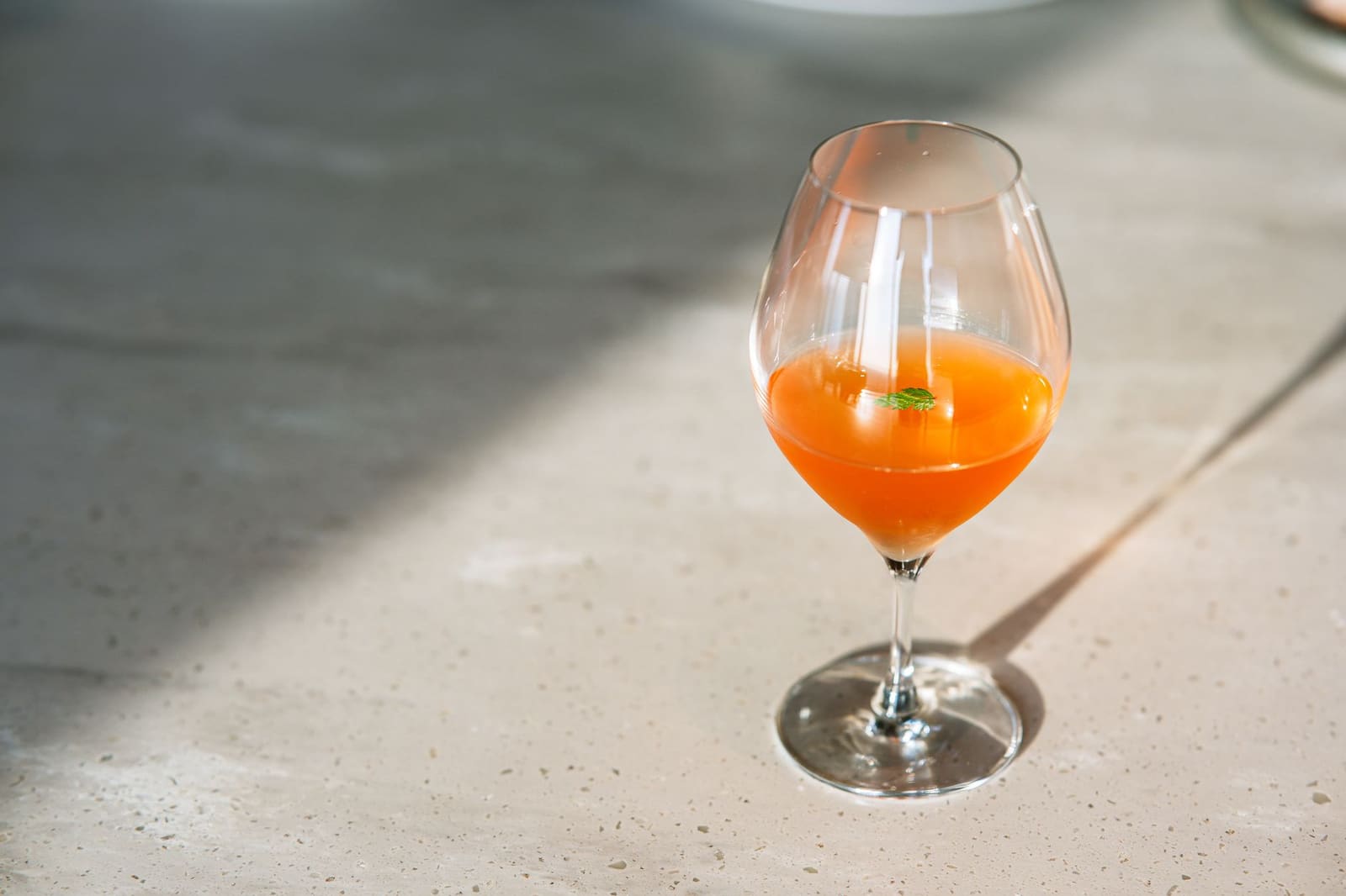 Oranje spritz in een wijnglas met een plakje sinaasappel en ijs op een terras.