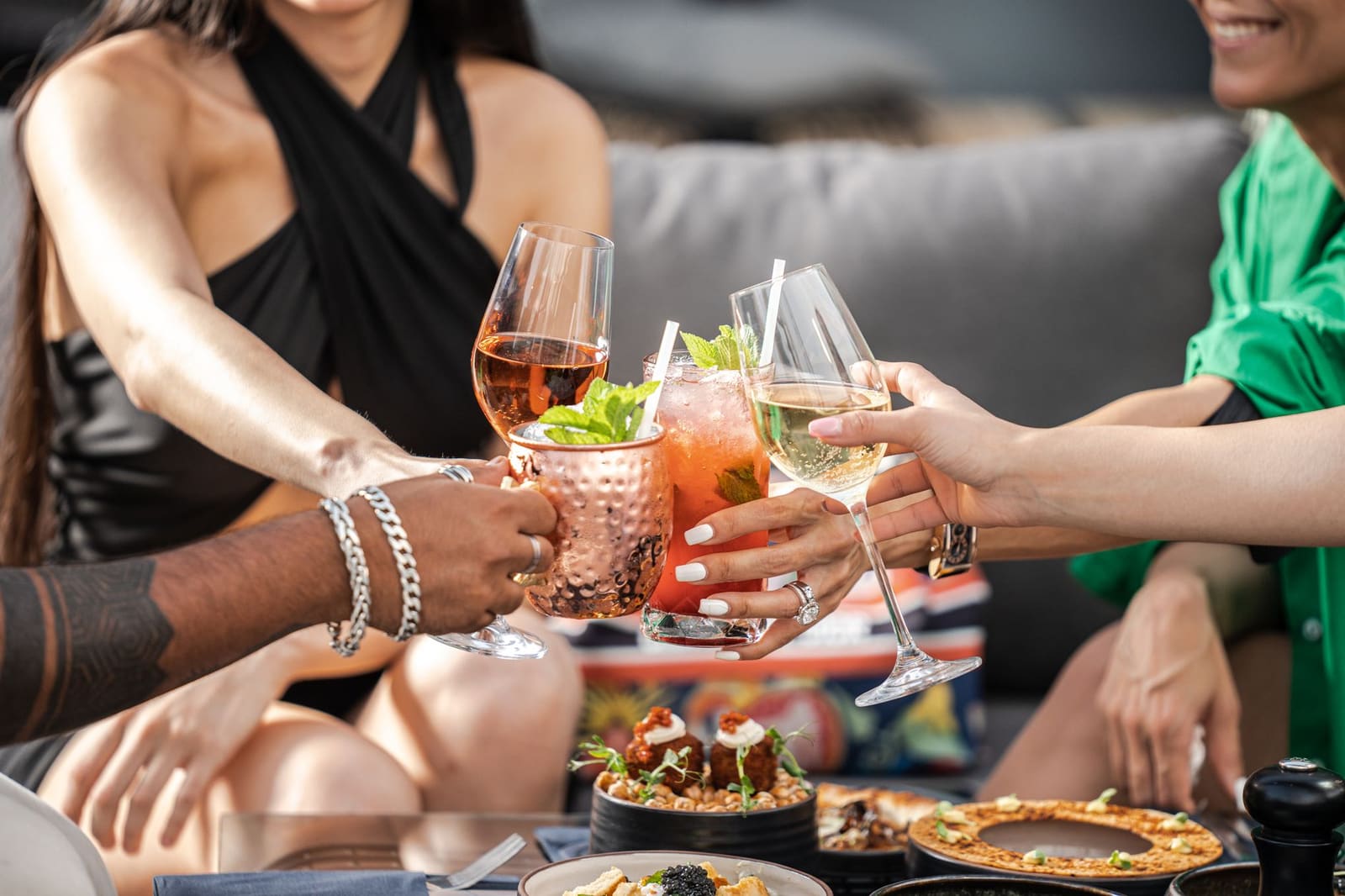 Vrienden zitten op een terras met glazen cocktails in het late avondlicht.