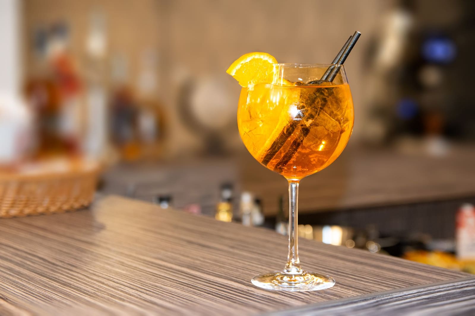 Close-up van een Aperol spritz met sinaasappelschijf in een groot glas