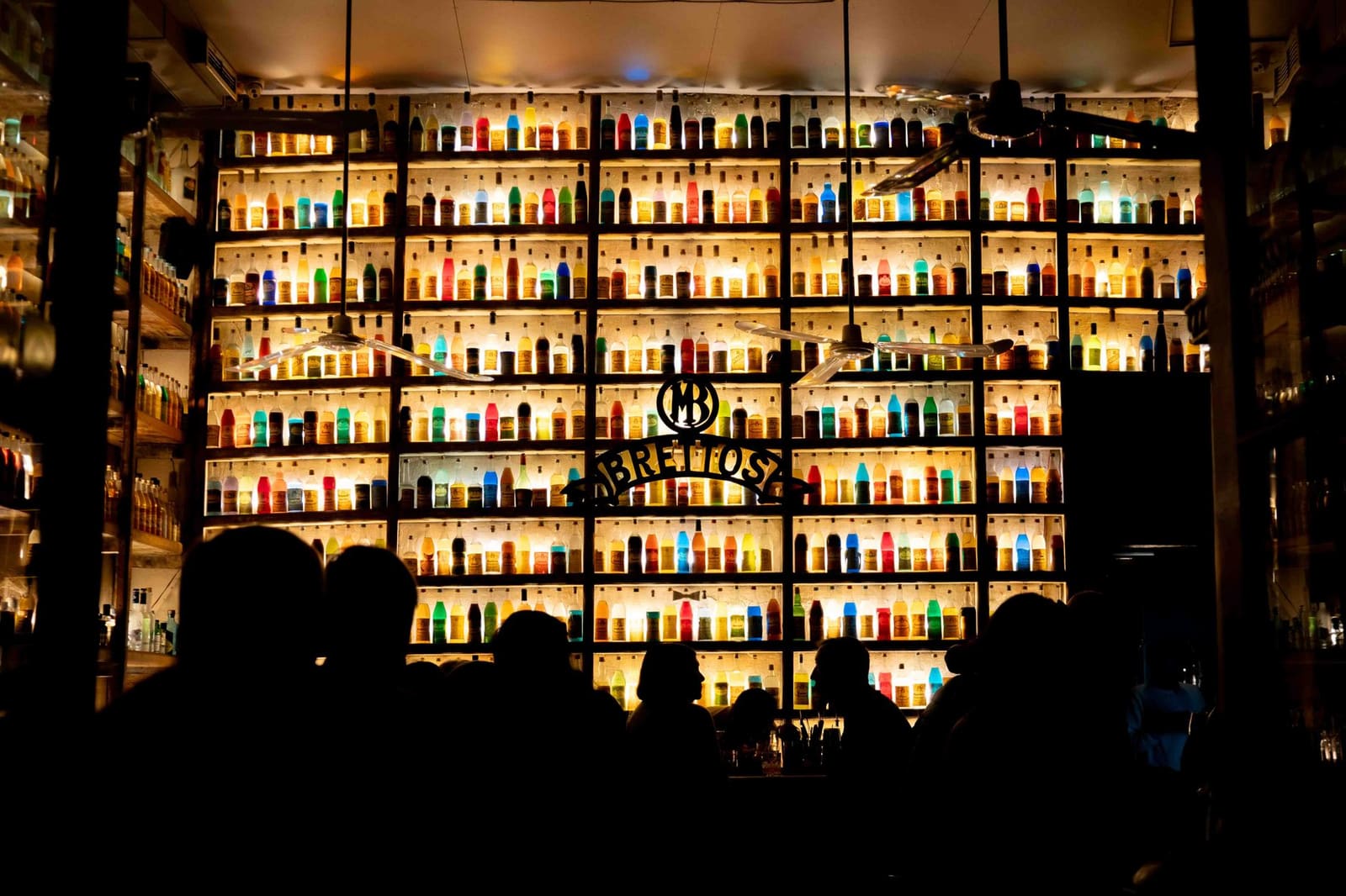 Fles amaretto op een backbar tussen andere drankflessen in een cocktailbar