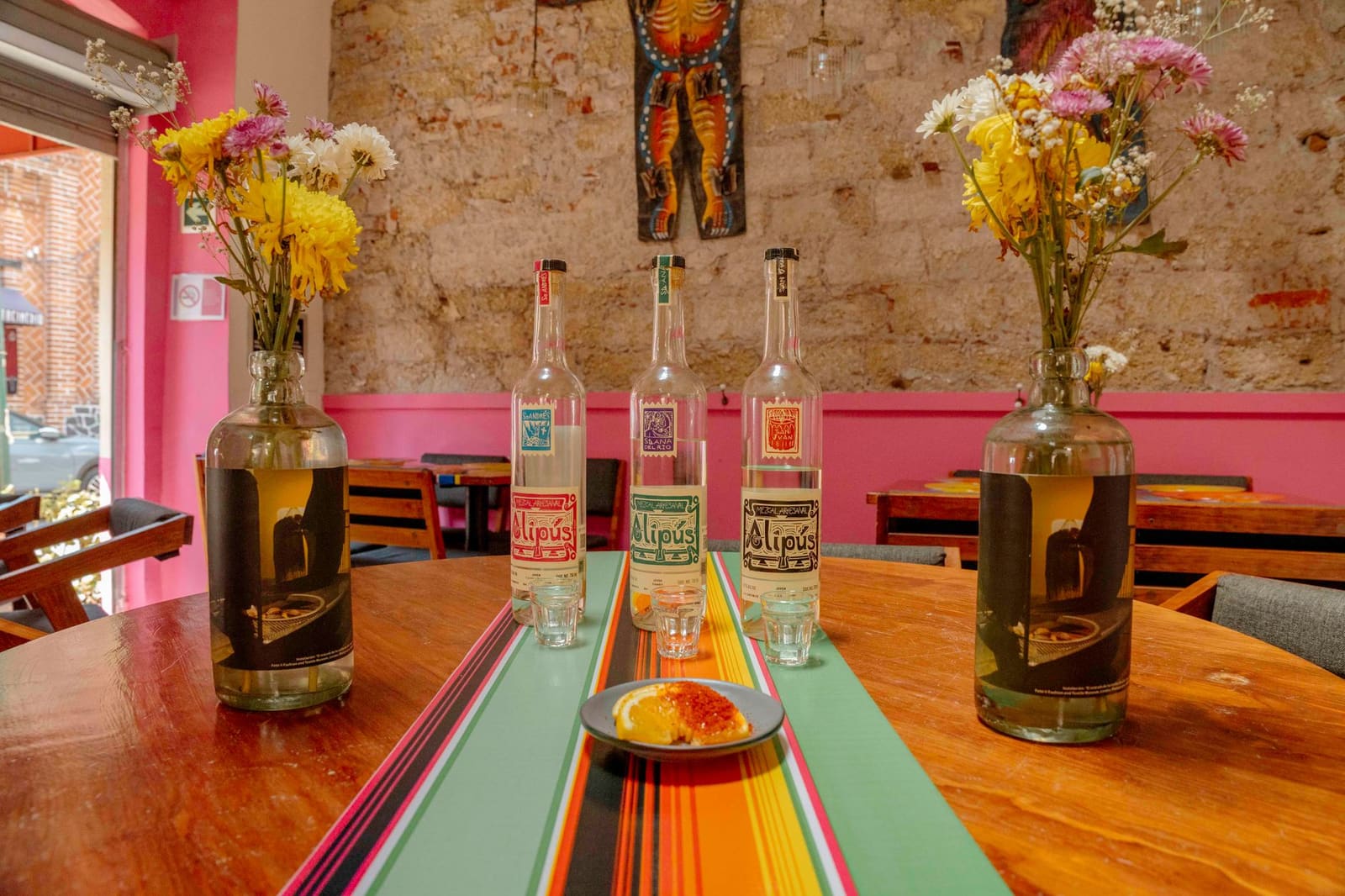Mezcal wordt uit een fles in een glas geschonken, met een schijf limoen ernaast.