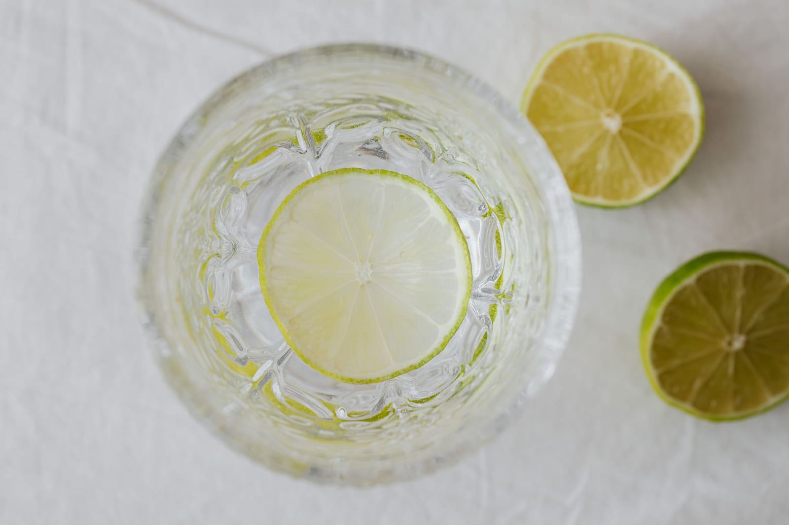 Gin tonic in een groot glas met ijs en een schijfje limoen op een terras.