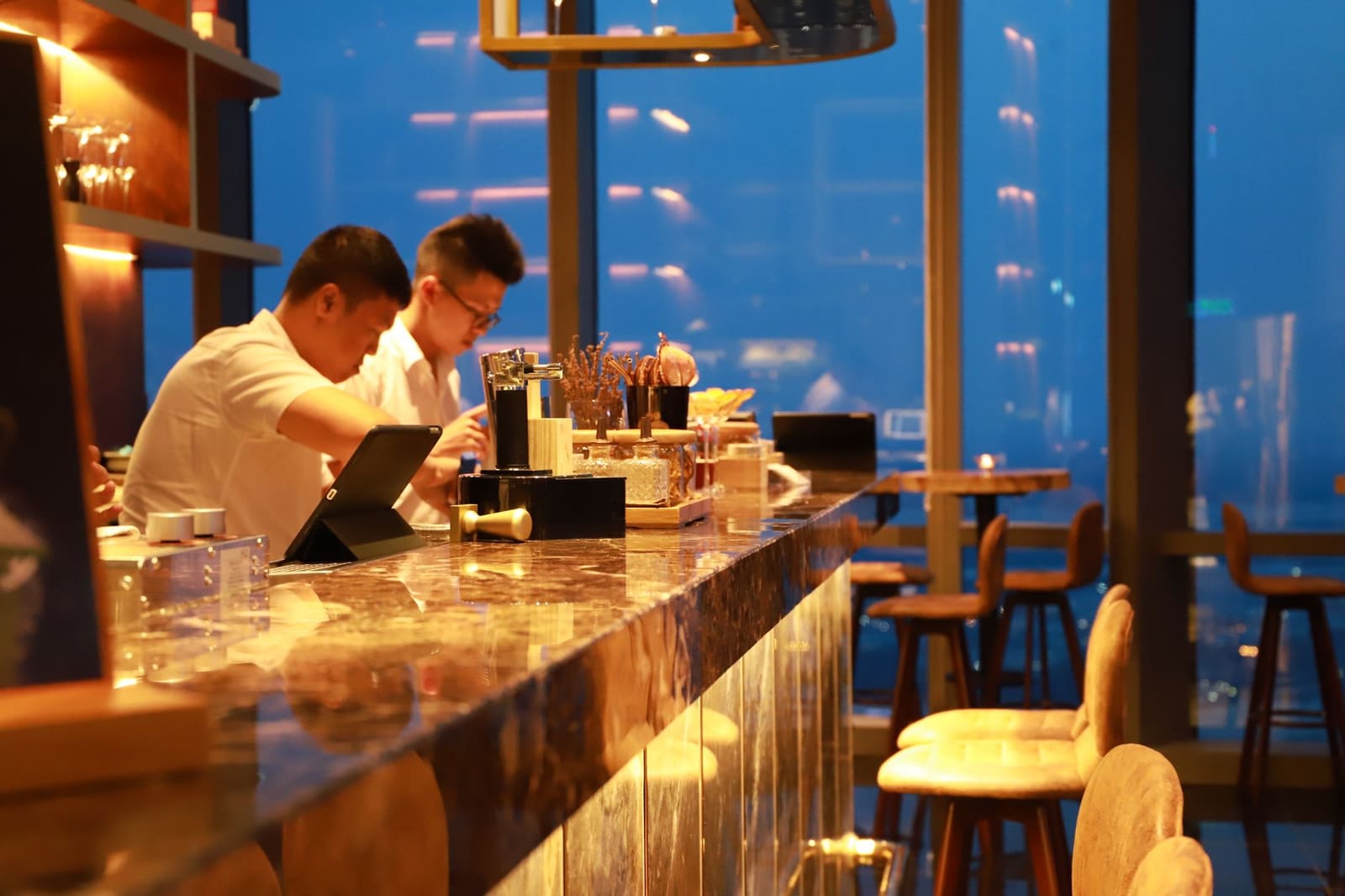 Sfeervolle cocktailbar met warm licht, flessen achter de toog en gasten aan de bar
