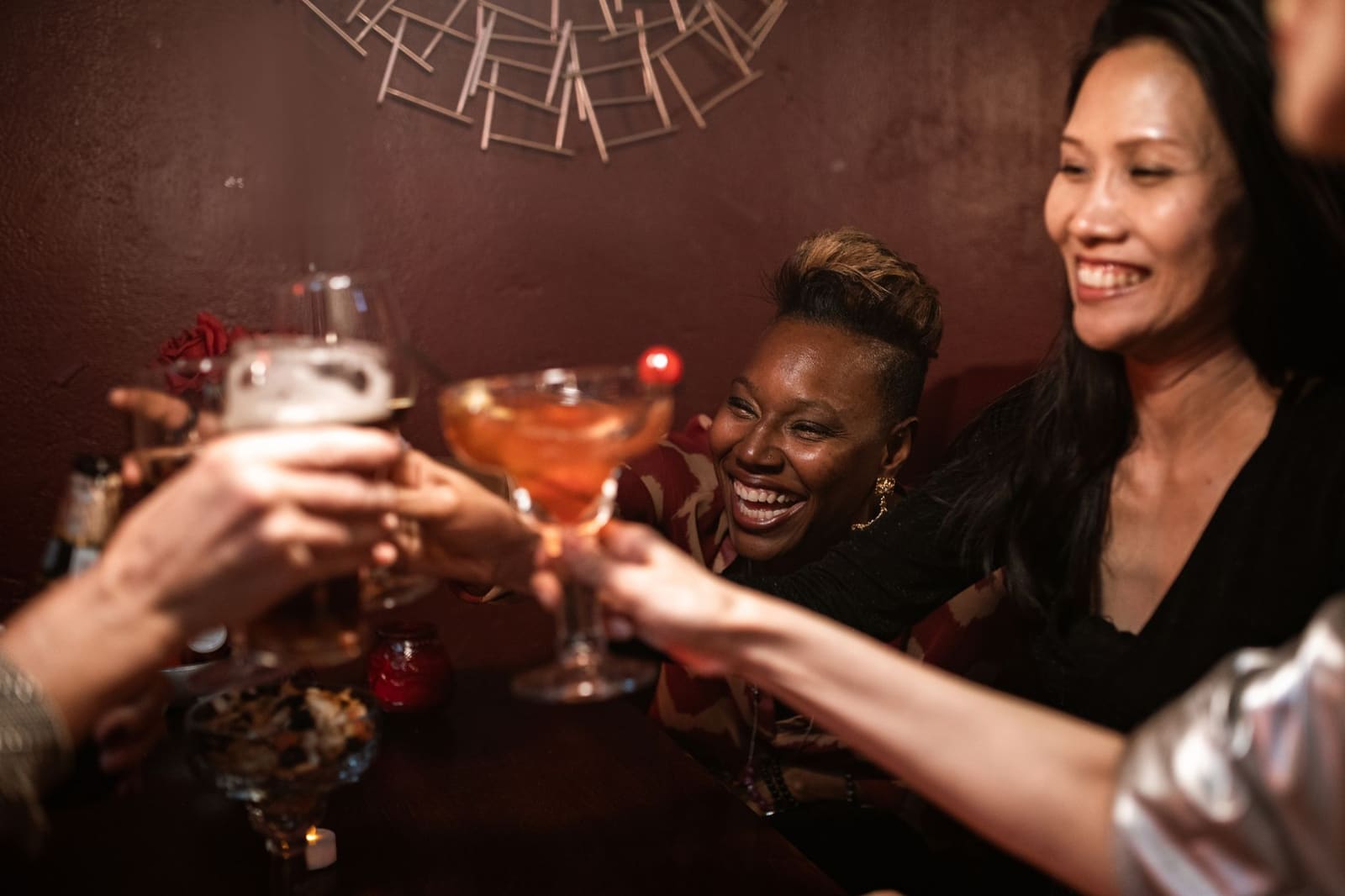 Gasten die met cocktailglazen proosten aan een bartafel tijdens een avond uit