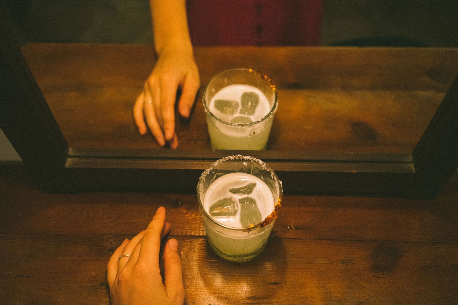 Handen van een bartender houden een shaker vast terwijl ijsblokjes door de lucht vliegen.