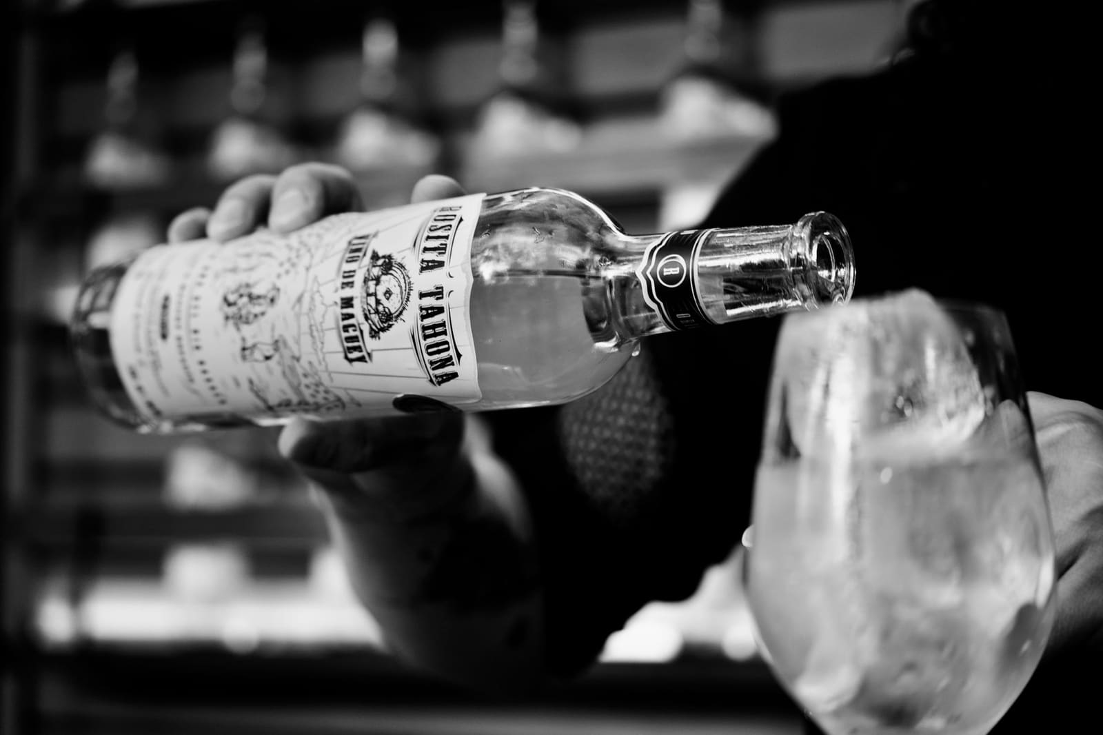 Tequila wordt uit een fles gegoten in een cocktailshaker op de bar