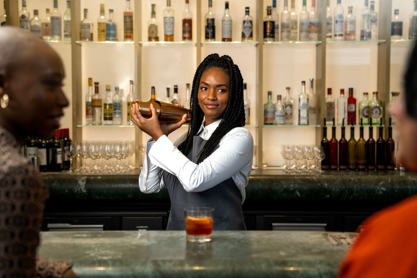 Bartender shaket een cocktail achter de bar in een cocktailglas