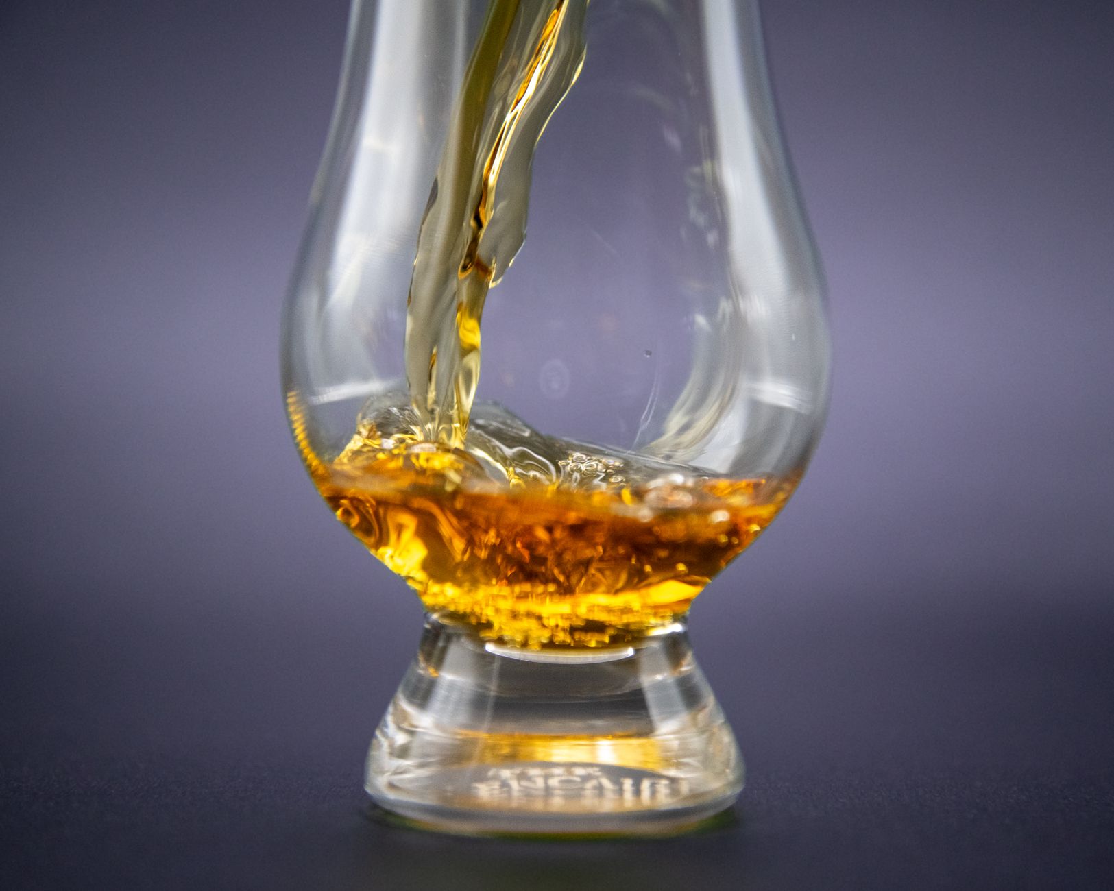 Glencairn-glas met scotch whisky tijdens een proeverij, met flessen op de achtergrond