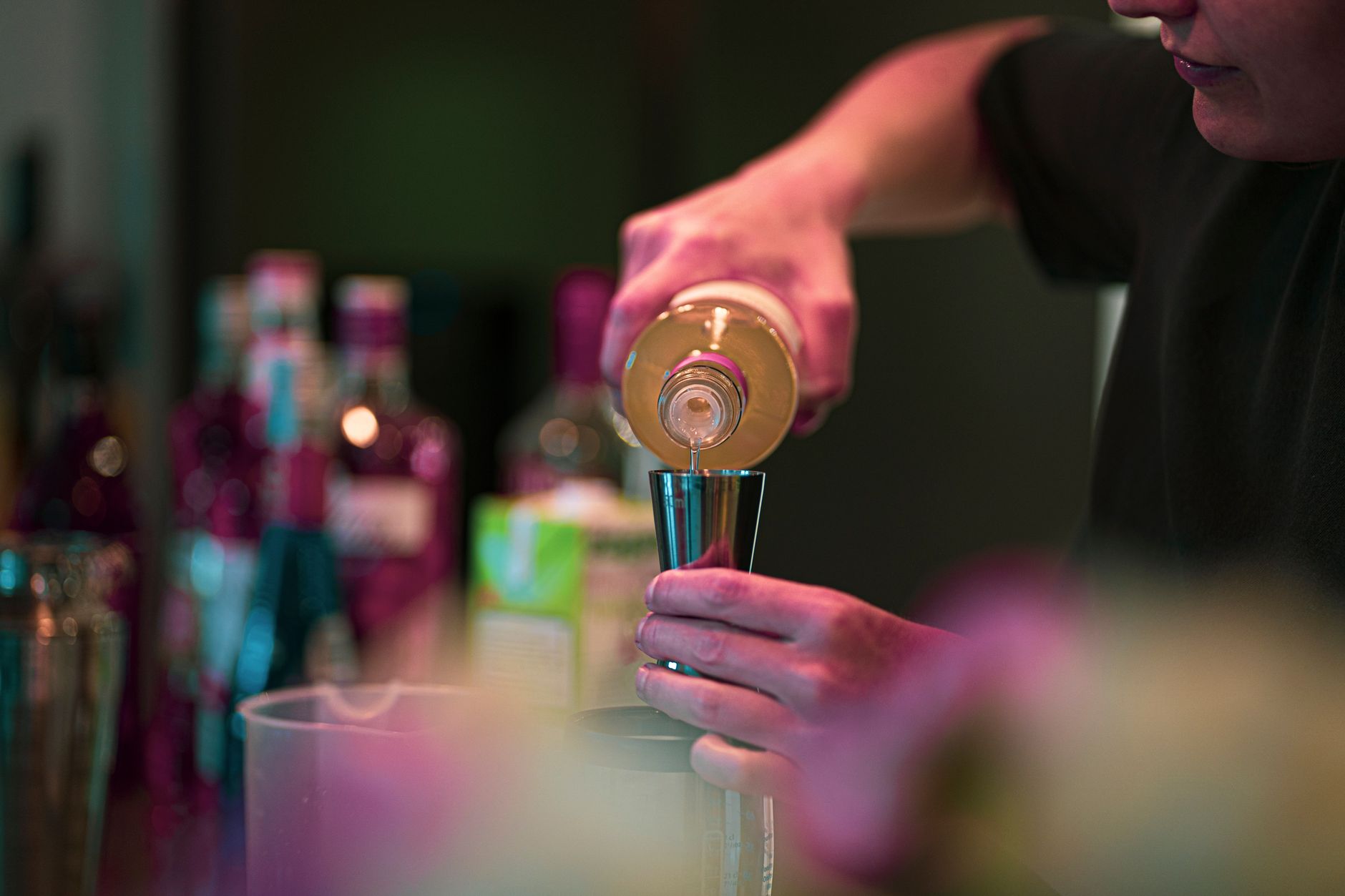 Bartender schenkt een gelaagde cocktail met slagroom erop achter de bar
