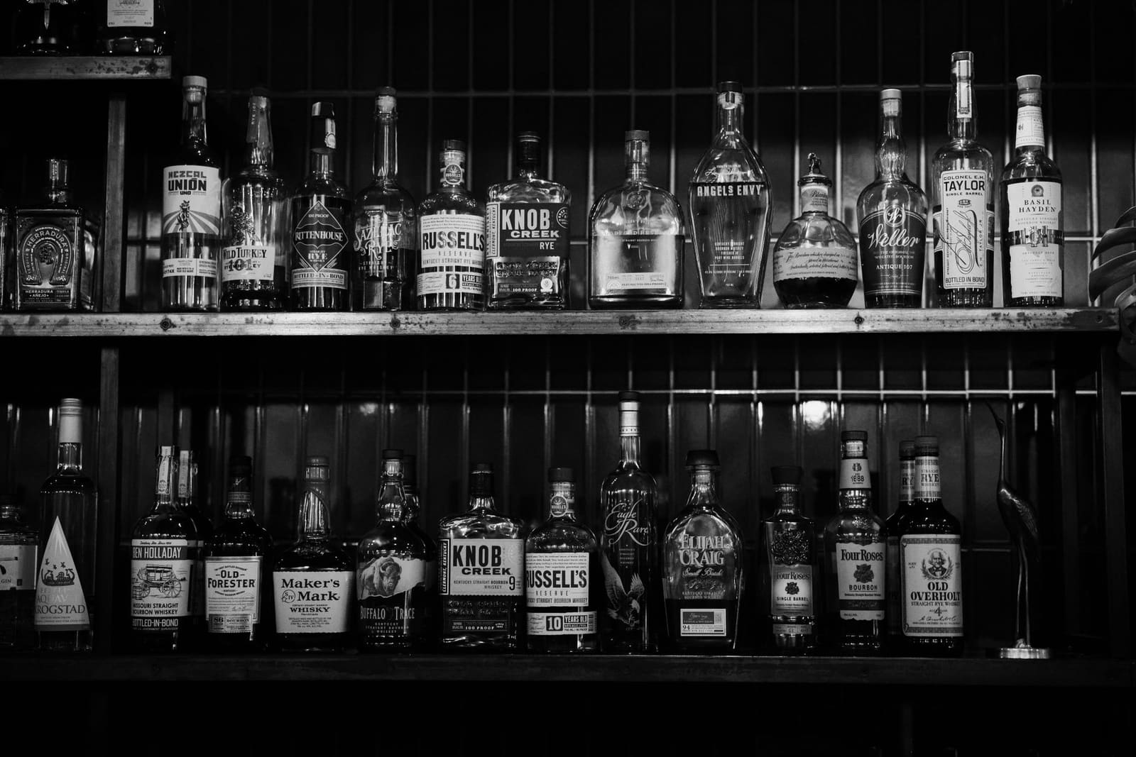Rij flessen bourbon whiskey opgesteld op een houten schap
