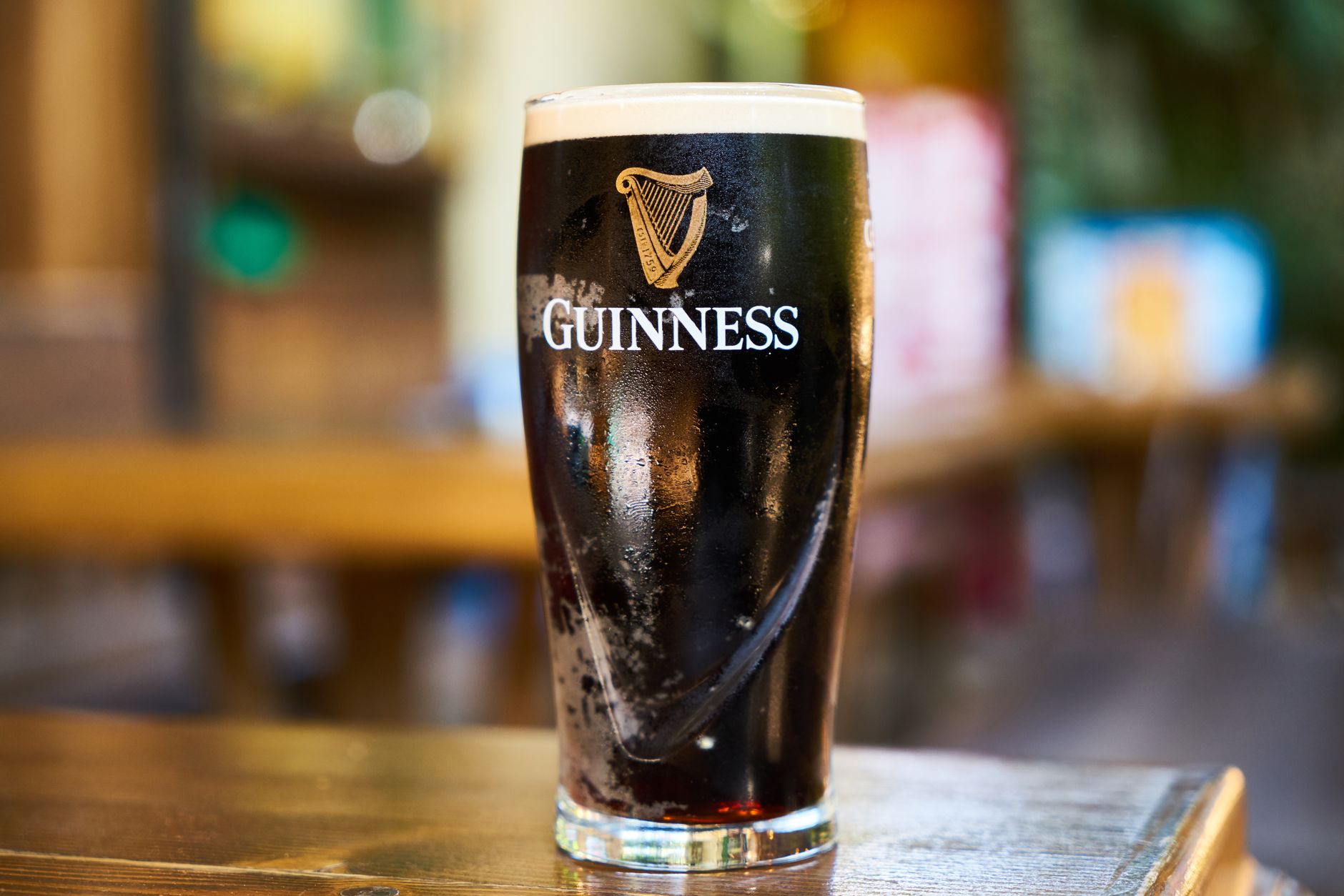 Een vers getapt glas Guinness stout met romige schuimkraag op een bar