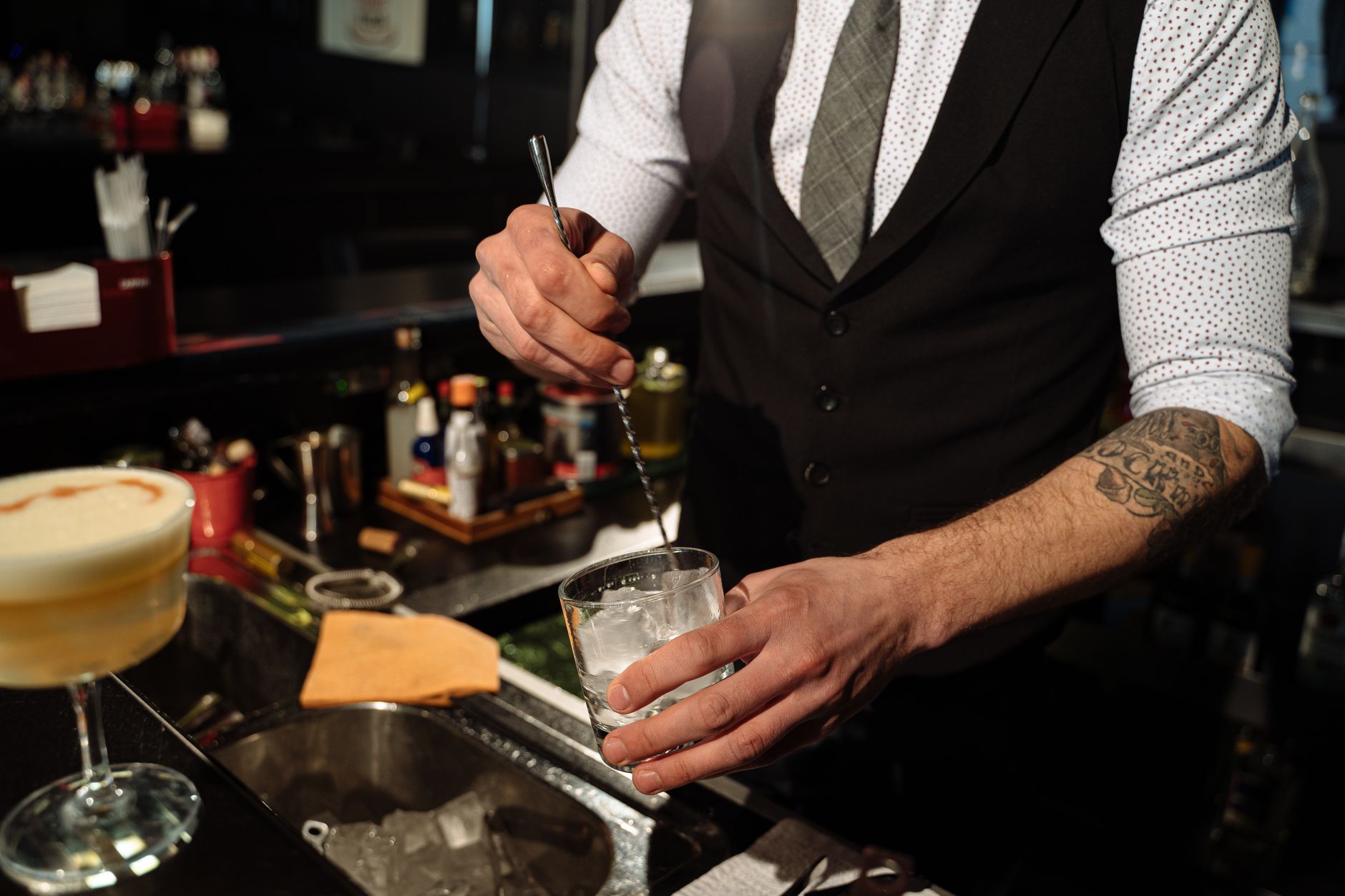 Bartender roert een Martini in een mengglas terwijl ijs en sterkedrank zich vermengen