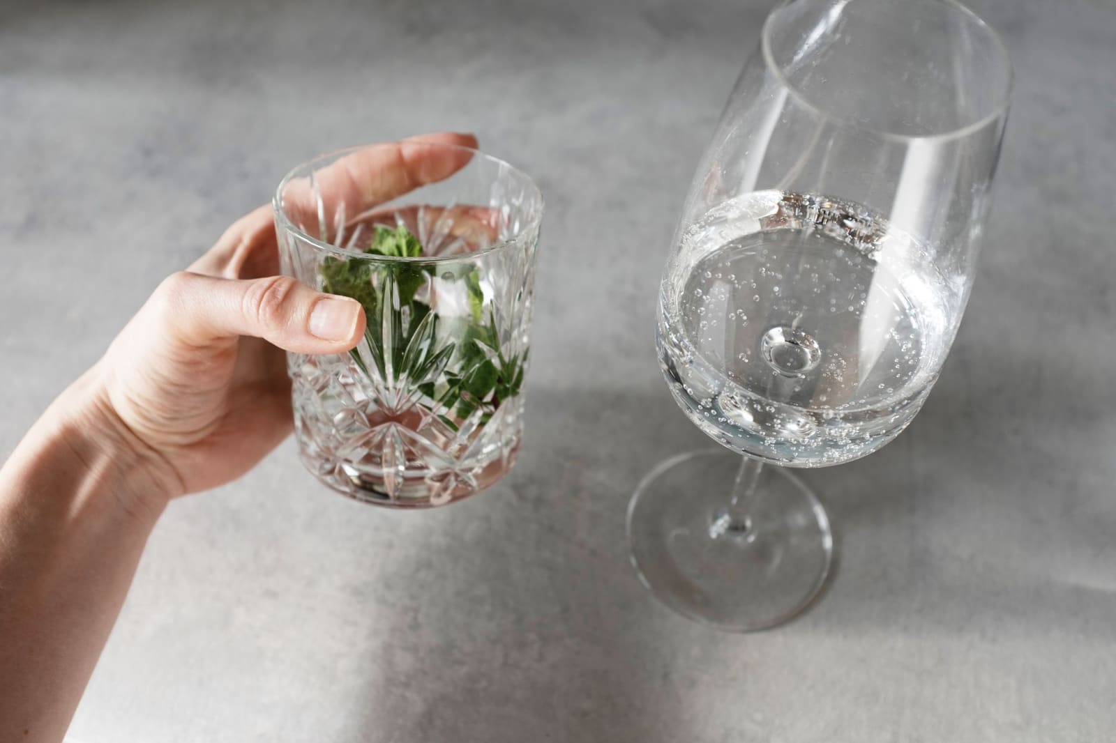 Gin tonic in een ruime ballonglas met munt en citrusschil op tafel