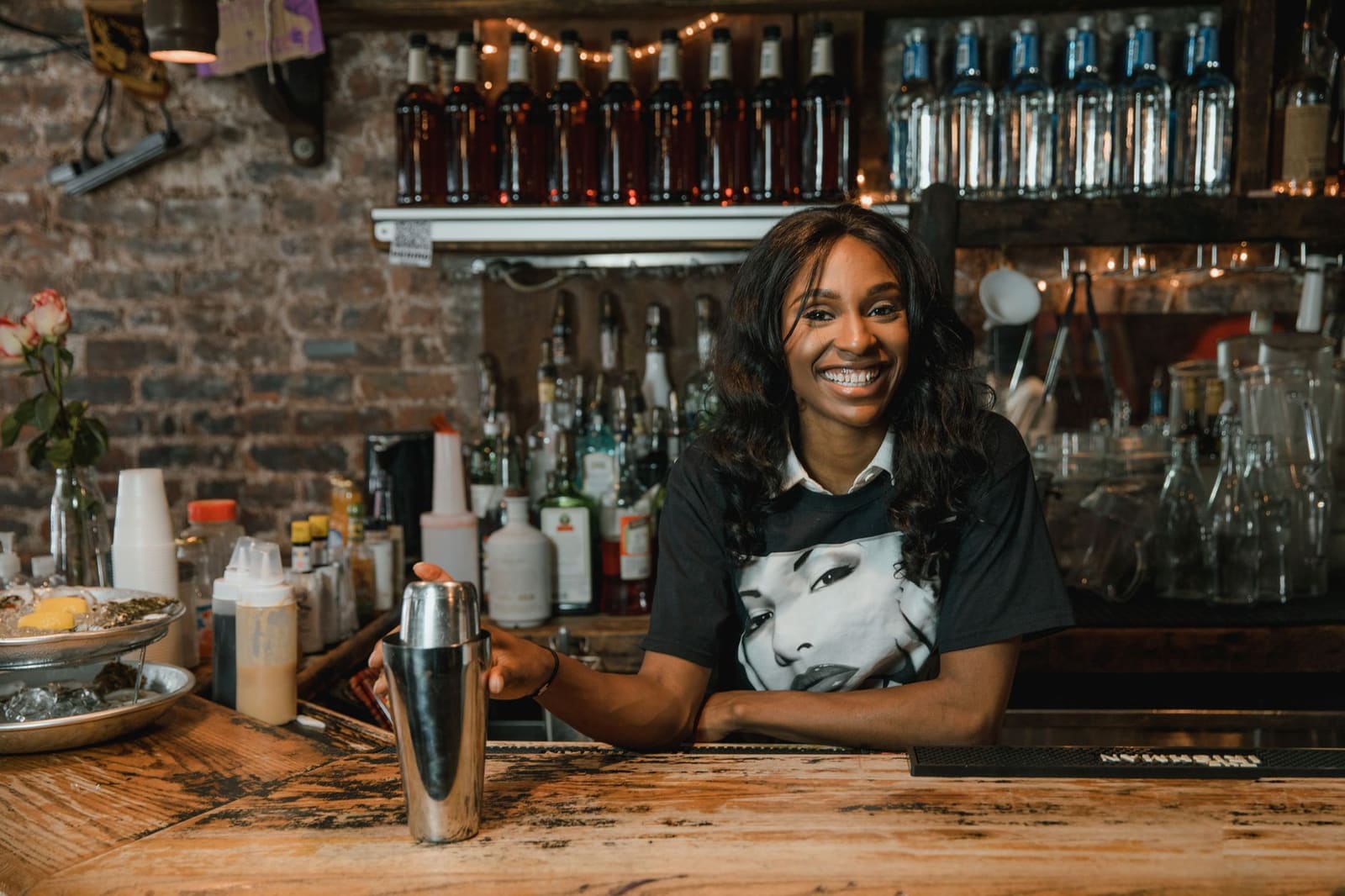 Een barman schudt een cocktailshaker vol met ijs boven de bar.