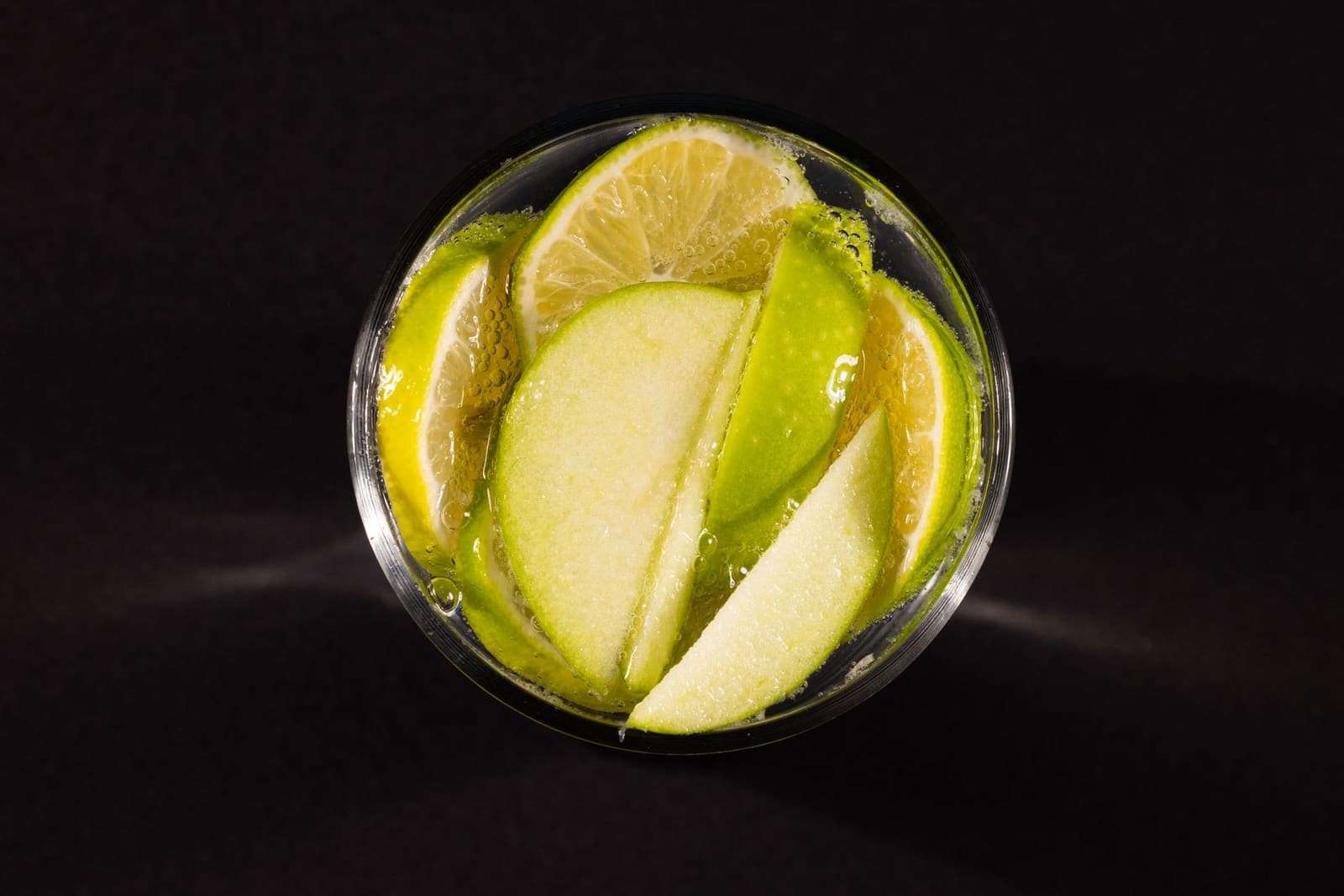 Een bruisende appel-spritz met ijsblokjes, appelschijfje en kaneelstokje als garnering