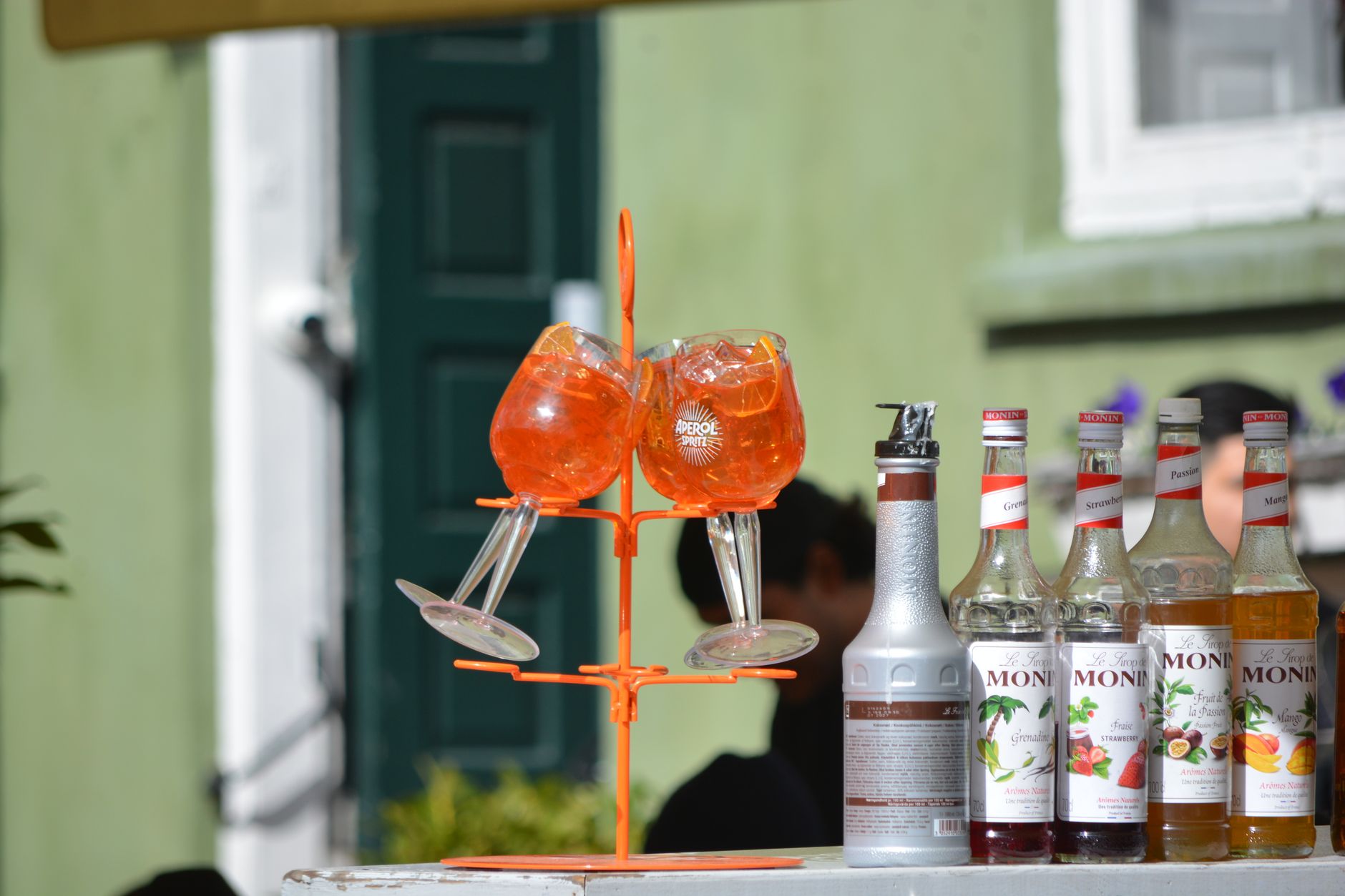 Rij gekleurde flessen cocktailsiroop en fruitpuree opgesteld achter de bar