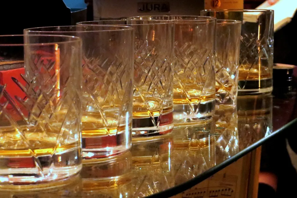 Glas whisky wordt geproefd tegen het licht op een houten bar