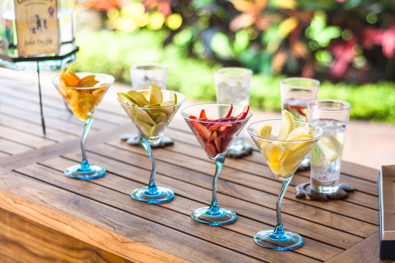 Verschillende kleurrijke cocktails naast elkaar op een houten tafel