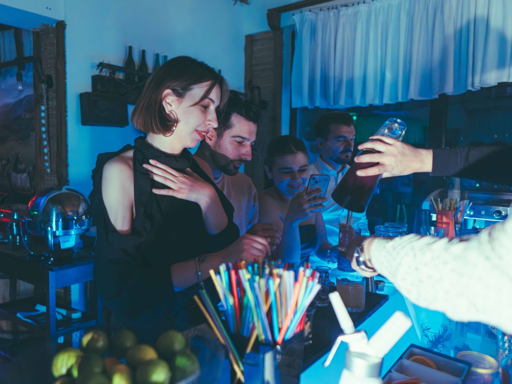 Groep jonge mensen proost met cocktails aan de bar tijdens een avond uit