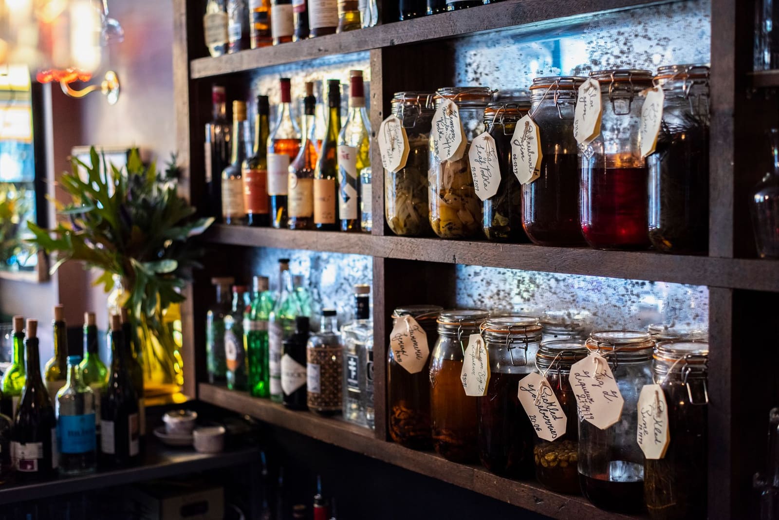 Fles kruidige alpenlikeur génépy naast een glas cocktail op een houten bar