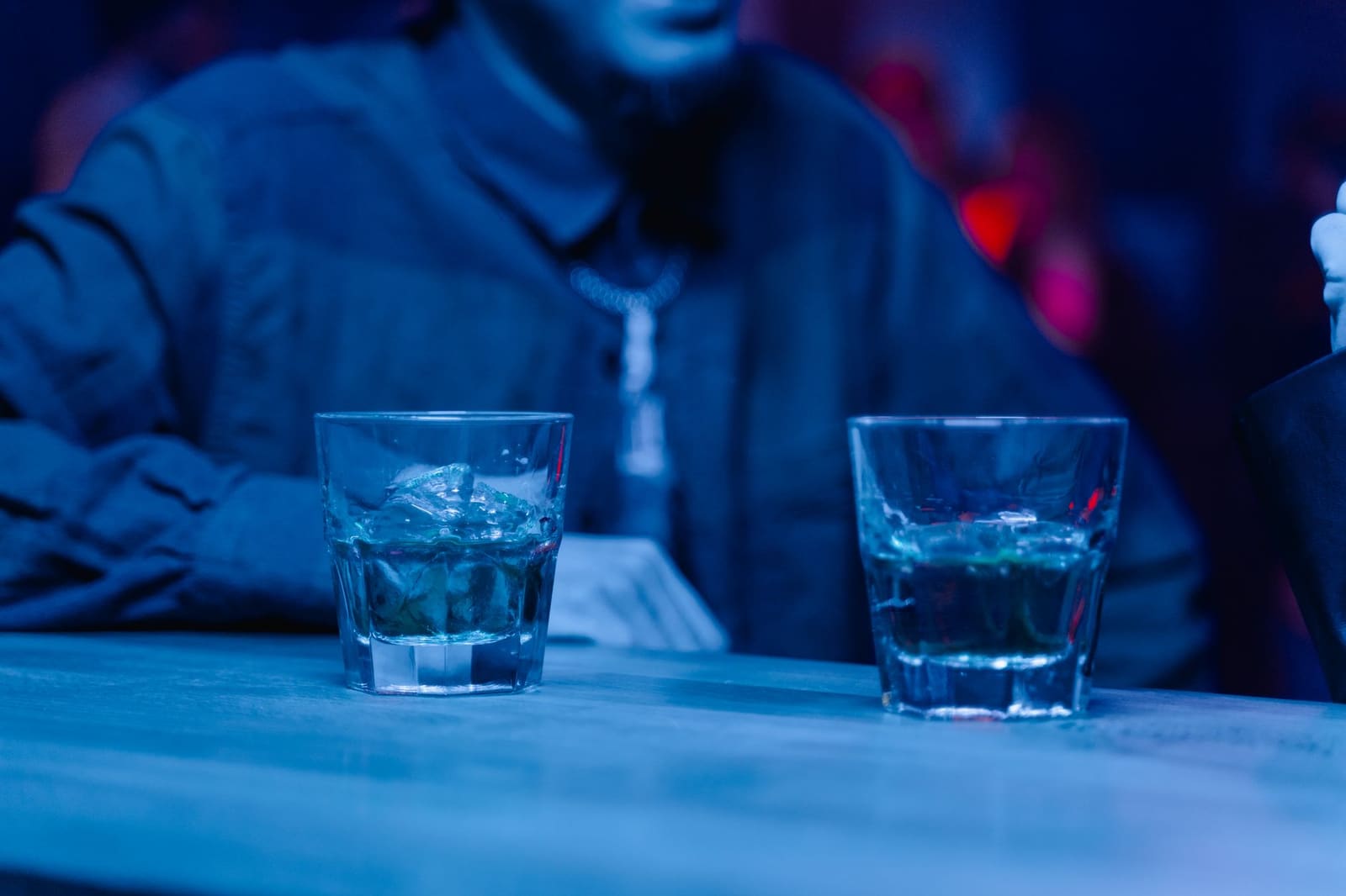 Cocktailglazen op een donkere bar met gedimd licht en een feestelijke, mysterieuze sfeer