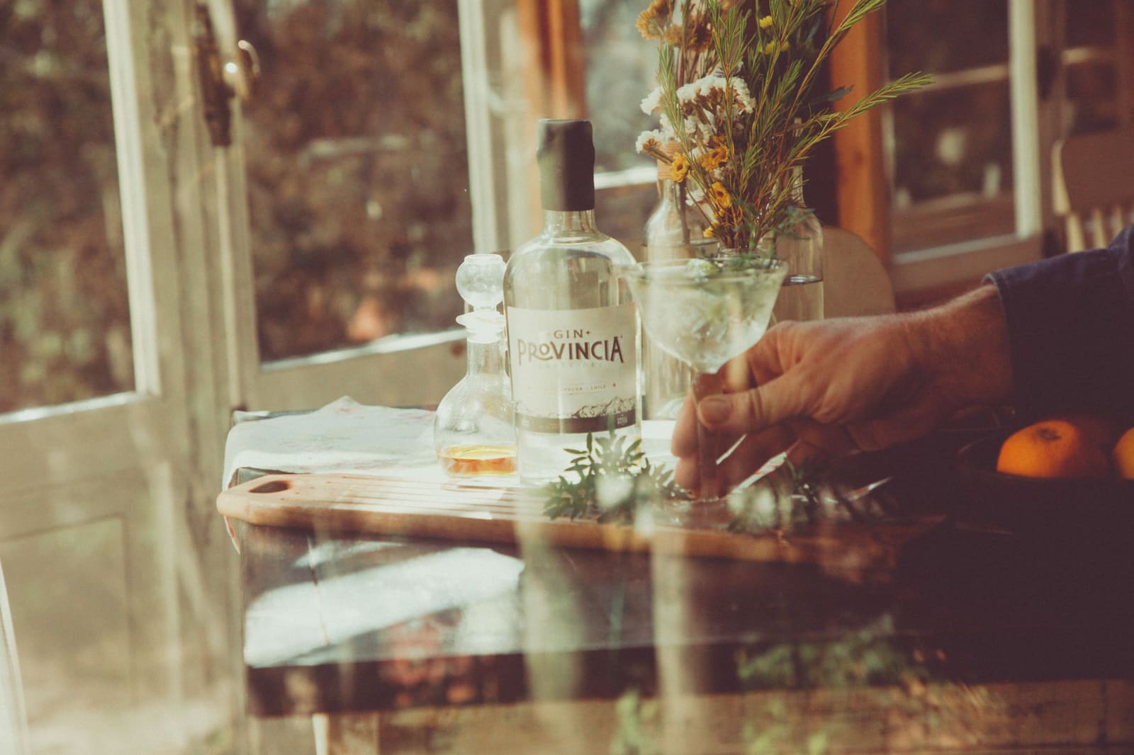 Fles gin met botanicals en kruiden uitgestald op een houten ondergrond