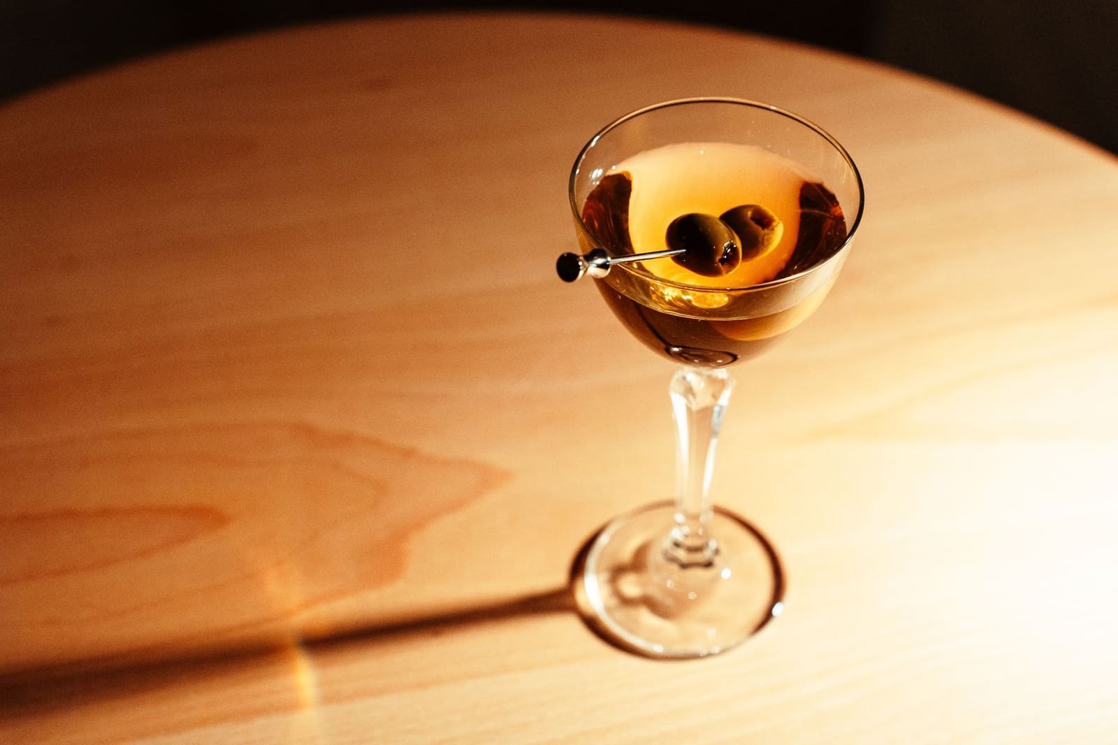 Een dirty martini met olijven in een gekoeld glas, klaar om geproefd te worden aan de bar
