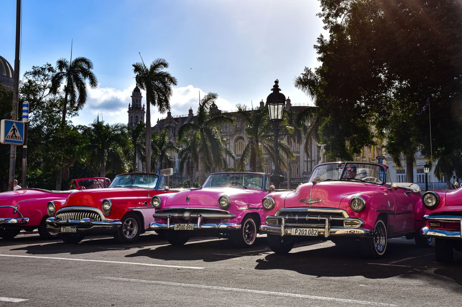 Oude Amerikaanse auto's rijden langs gekleurde huizen in Havana