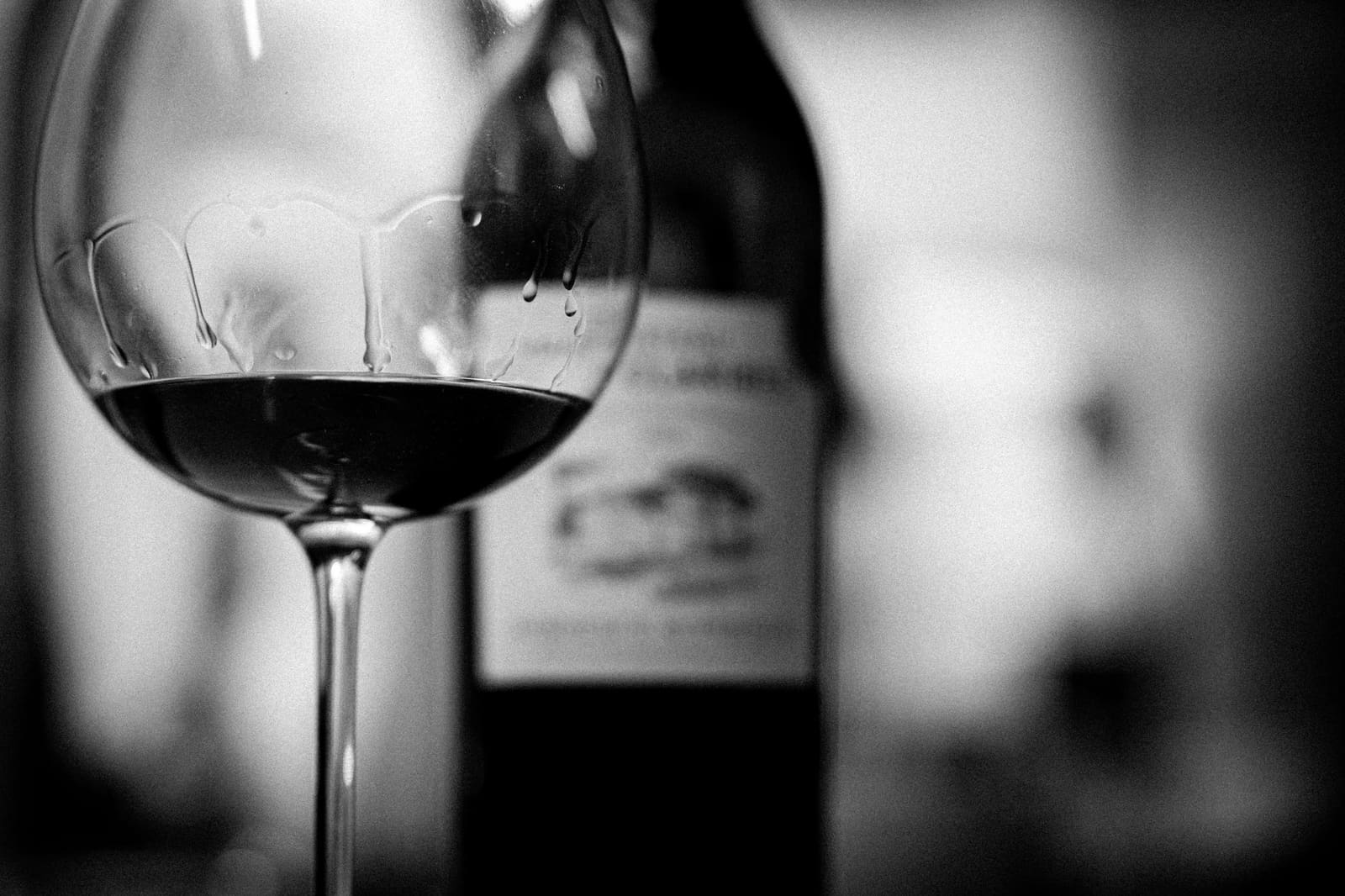 Een fles cognac naast een bolvormig glas op een houten tafel